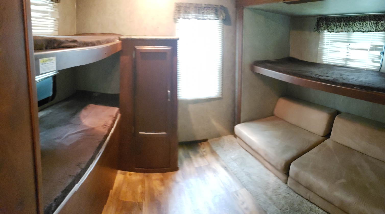 Spacious RV rental interior with comfortable bunk beds, sofa seating, and bright window. Perfect for families.. Keystone RV Passport Grand Touring 2016