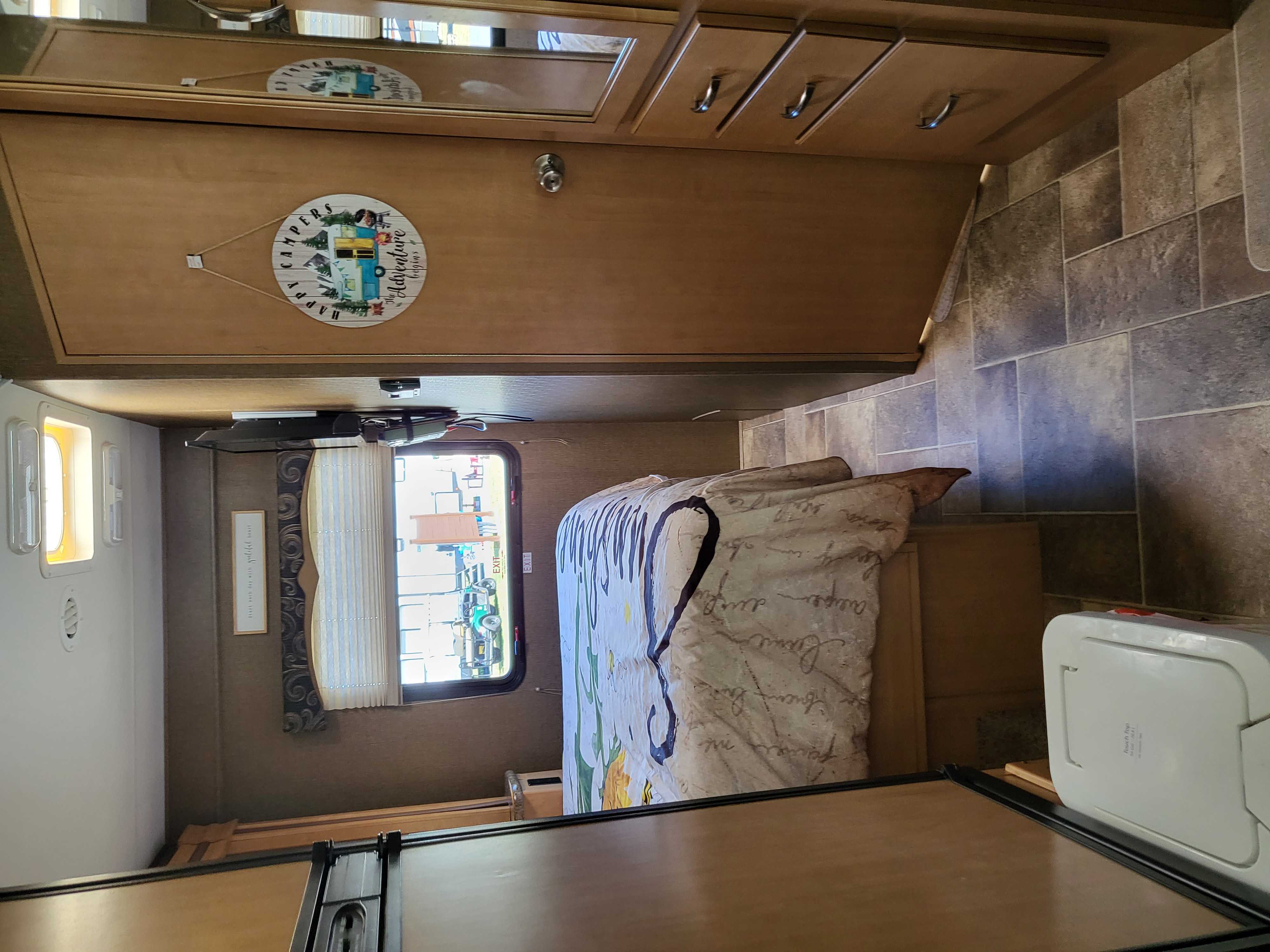 Cozy bedroom interior of an rv rental, featuring a comfortable bed, window, and storage cabinets, ready for adventure.. Thor Four Winds 2016