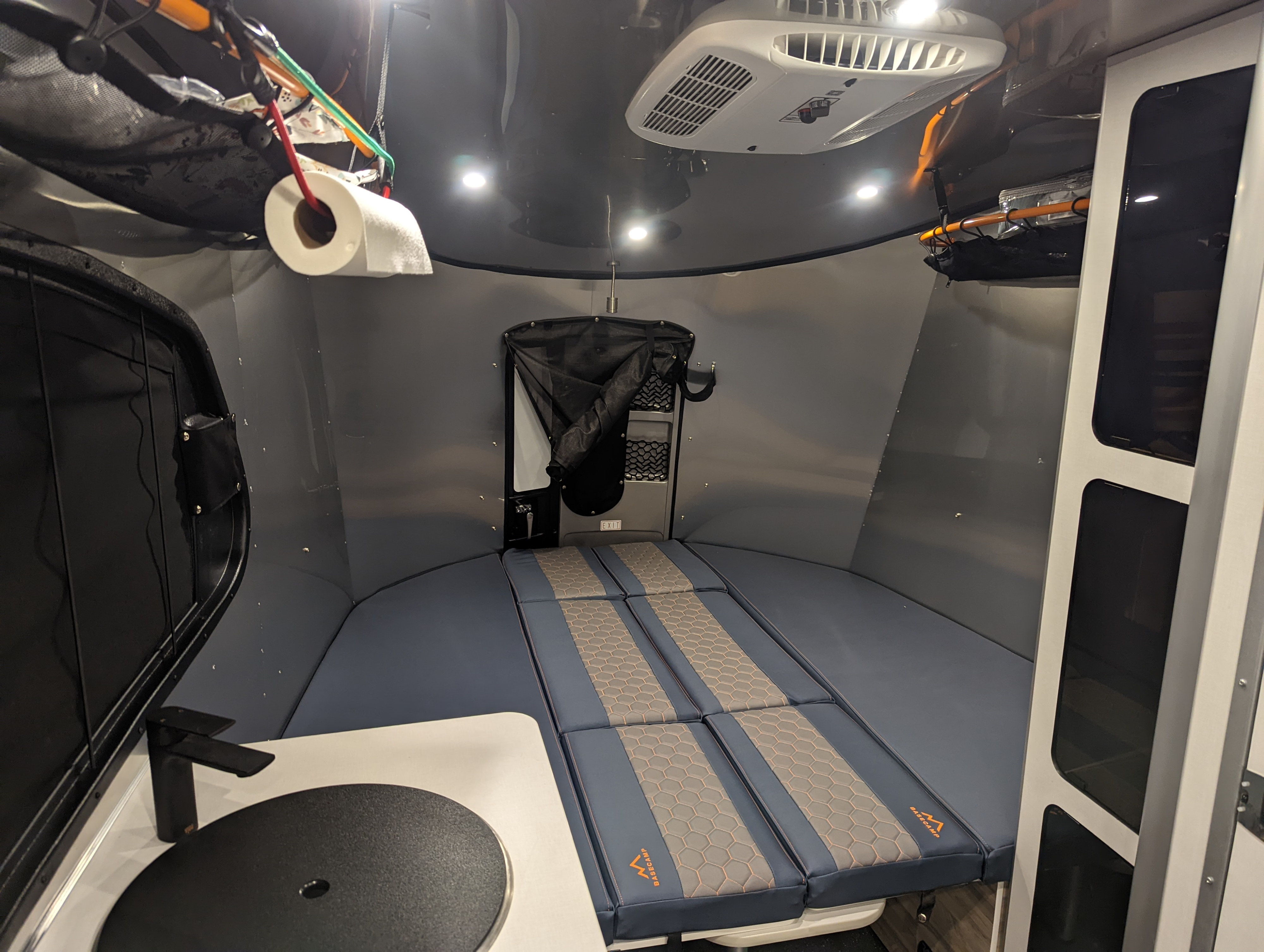 Cozy RV rental interior with a convertible bed, small kitchen area, and overhead storage, ready for adventure.. Airstream Basecamp 2022