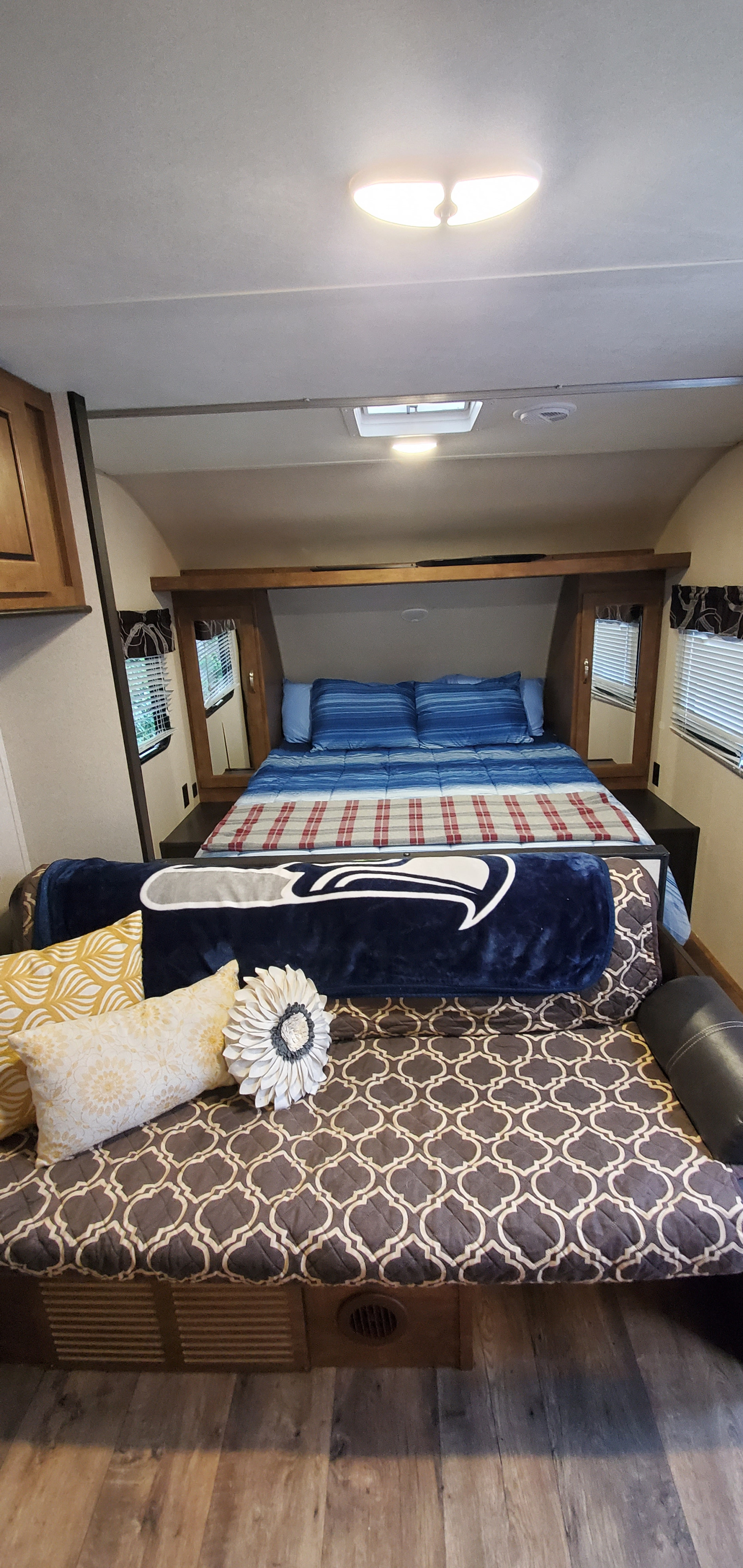 RV rental interior featuring a cozy bedroom area with blue bedding, a Seahawks blanket, and a patterned living space with pillows.. Forest River Salem Cruise Lite 2018