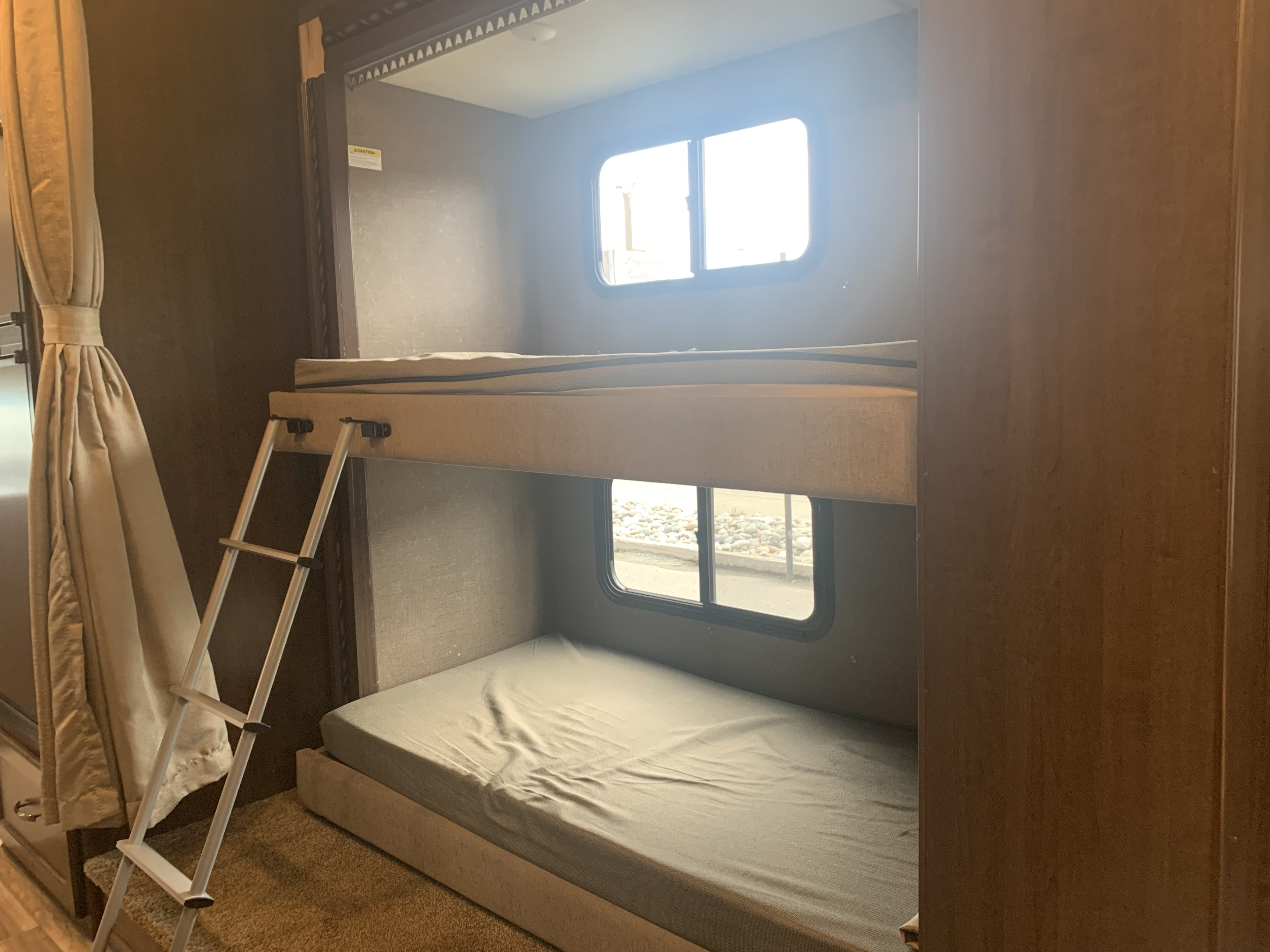 Cozy RV rental interior with bunk beds, ladder, and windows, ideal for family trips.. Thor Motor Coach Four Winds 2018