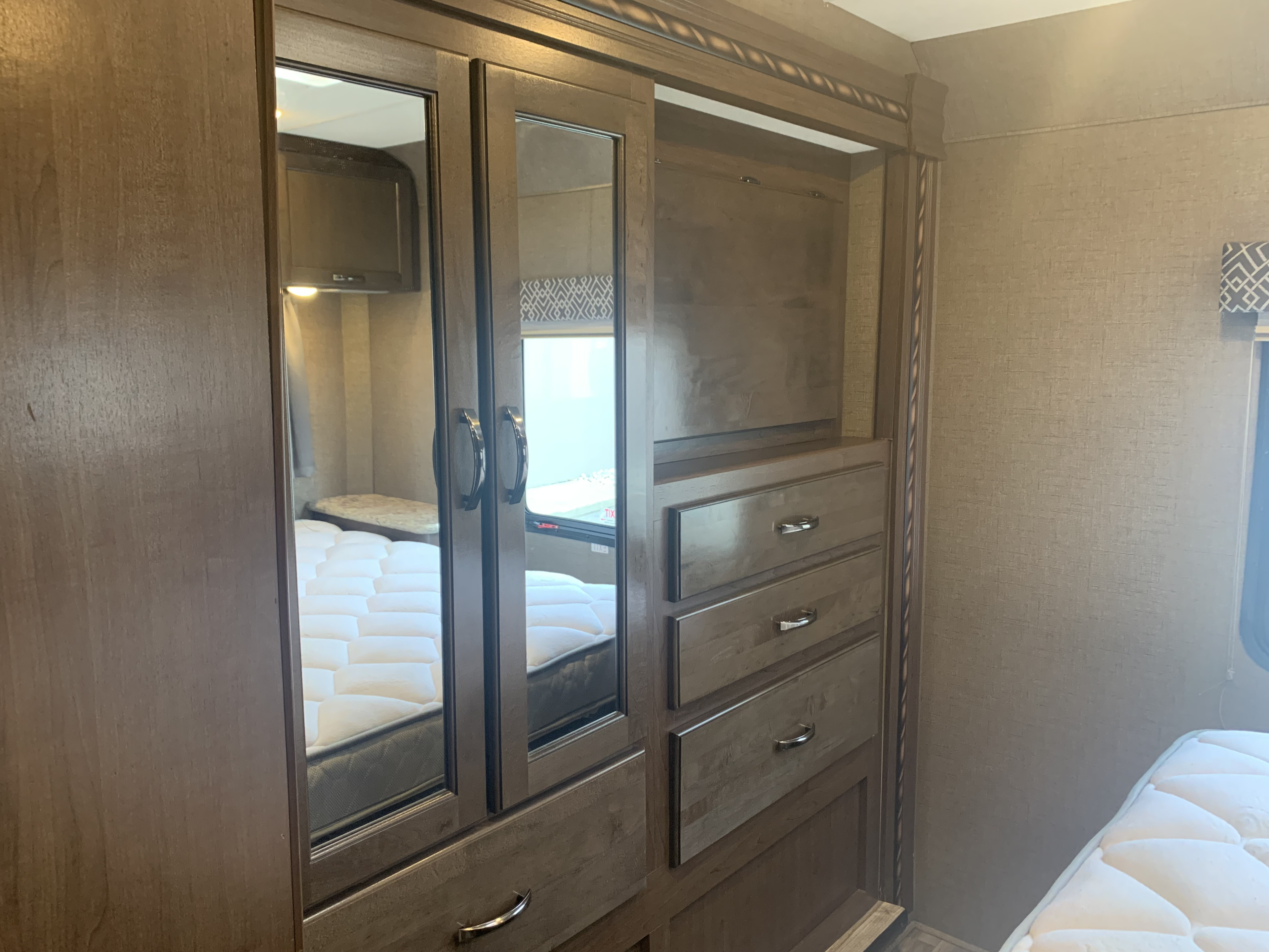 RV rental interior: Mirrored closet doors, built-in drawers, and a comfortable bed in a well-designed bedroom.. Thor Motor Coach Four Winds 2018