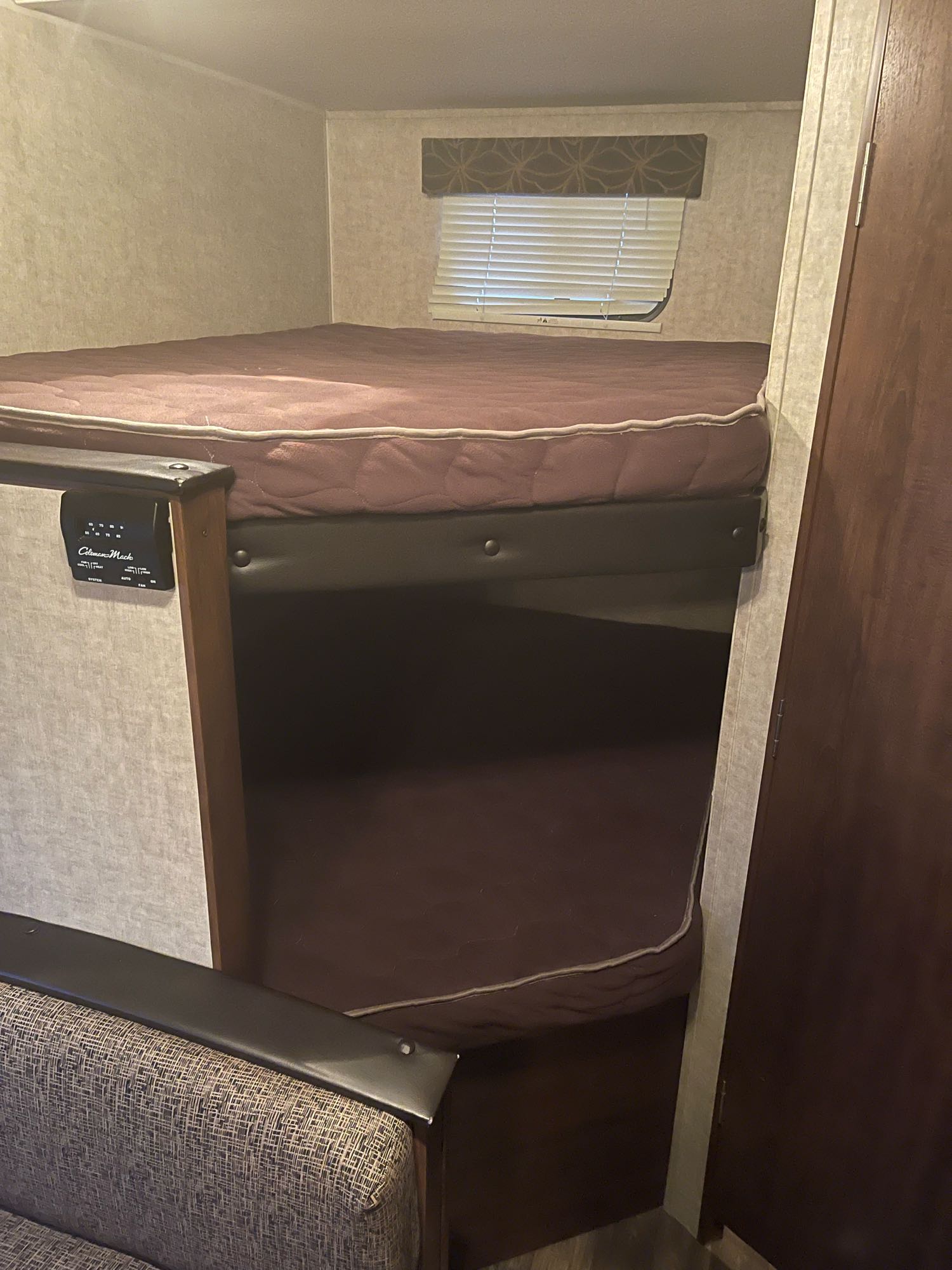 RV rental bunk beds: a cozy interior sleeping area with top and bottom bunks, window, and climate control panel.. Keystone Hideout 2016