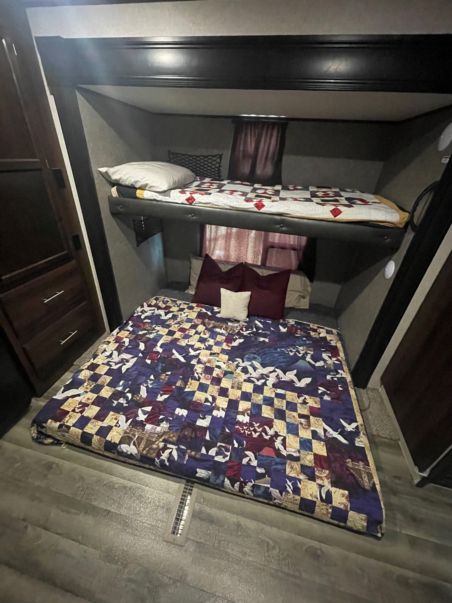 A compact RV rental bedroom features two comfortable bunk beds with colorful quilts and a small dresser.. Jayco Jay Flight 2019