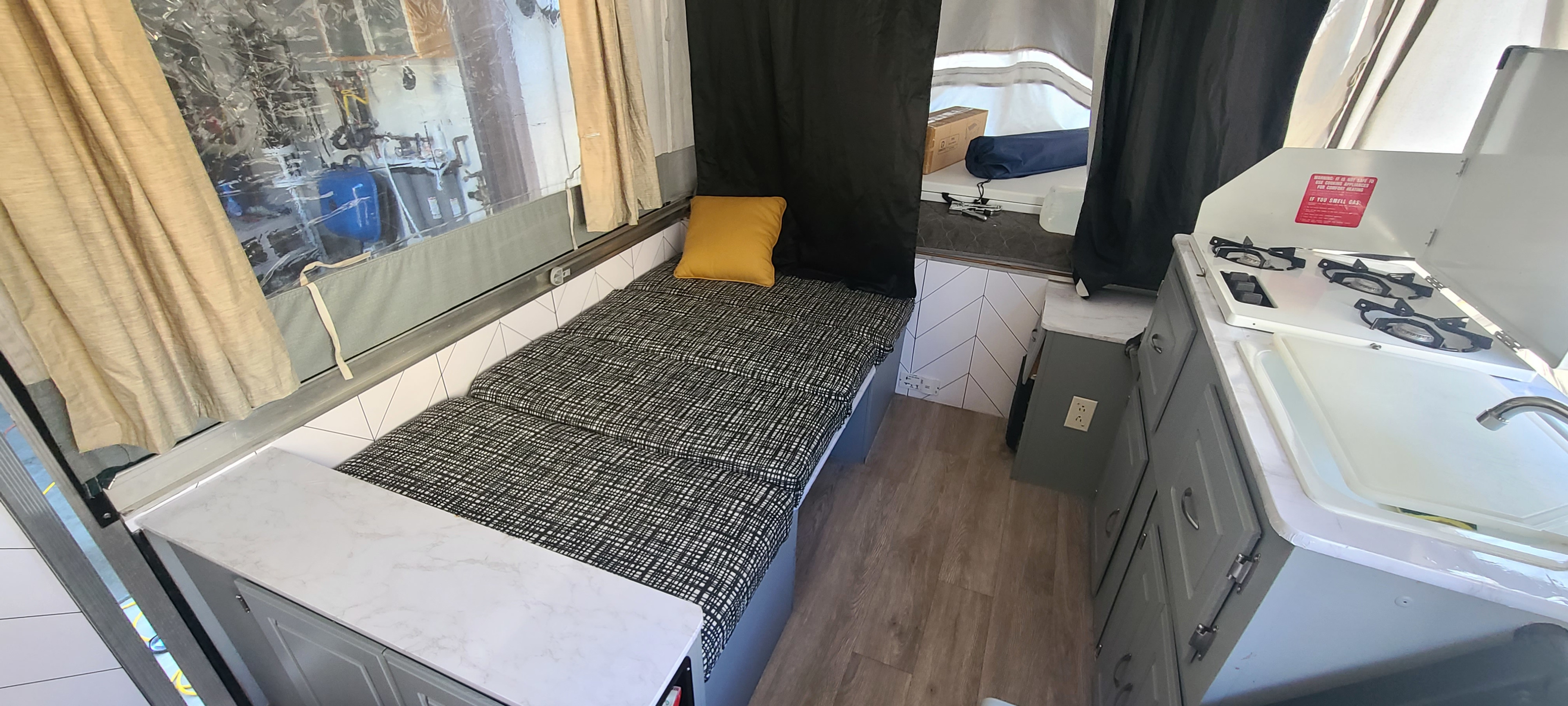 Explore this modern RV rental interior! Features a comfy bed, functional kitchen with stove and sink, and bright, inviting space.. Coleman Grand Tour 2001