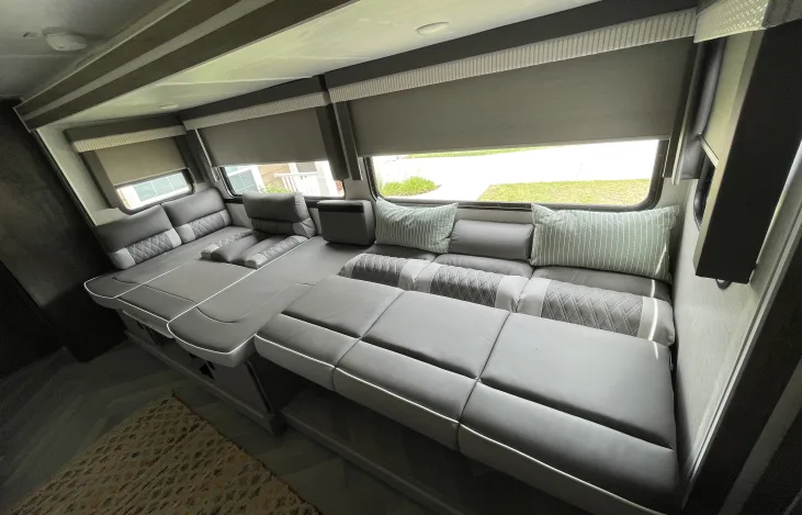 Versatile RV rental interior with modern gray modular seating and windows. Transforms for lounging or sleeping.. Forest River Wildwood X-Lite 2022