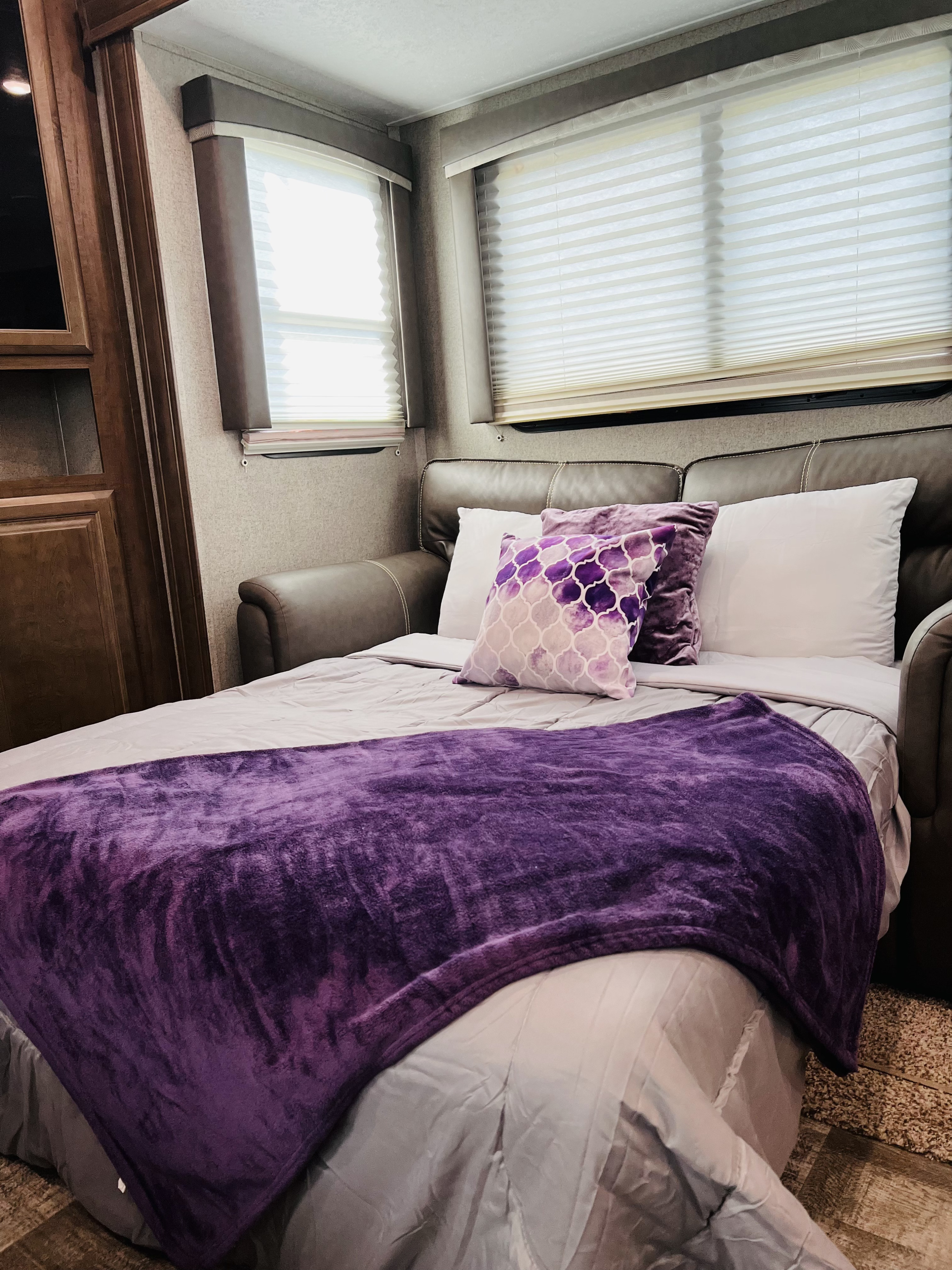 Cozy RV rental interior with a sofa converted into a bed, featuring a vibrant purple blanket and decorative pillows.. Forest River Rockwood Ultra Lite 2020