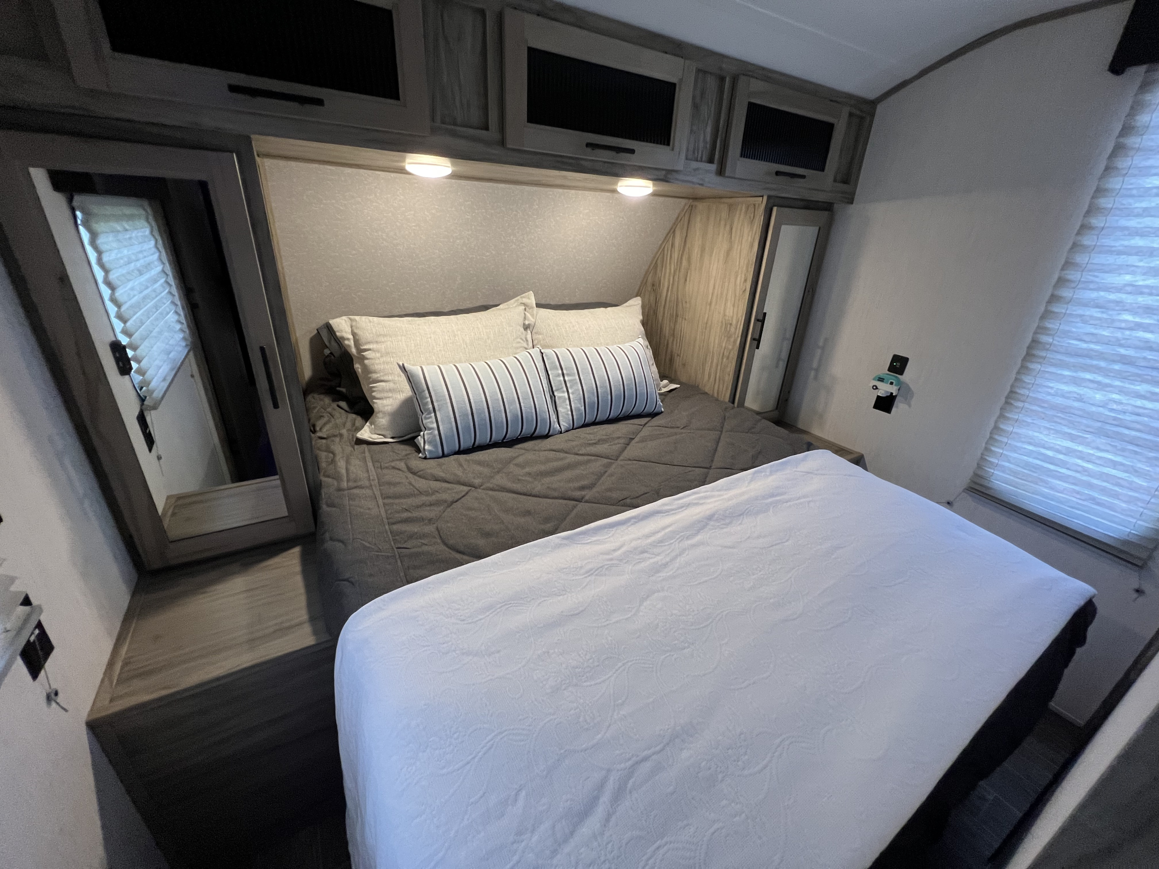 Experience comfort in this RV rental bedroom, featuring a queen bed, overhead storage, and ambient reading lights.. Forest River Cherokee Alpha Wolf 2022