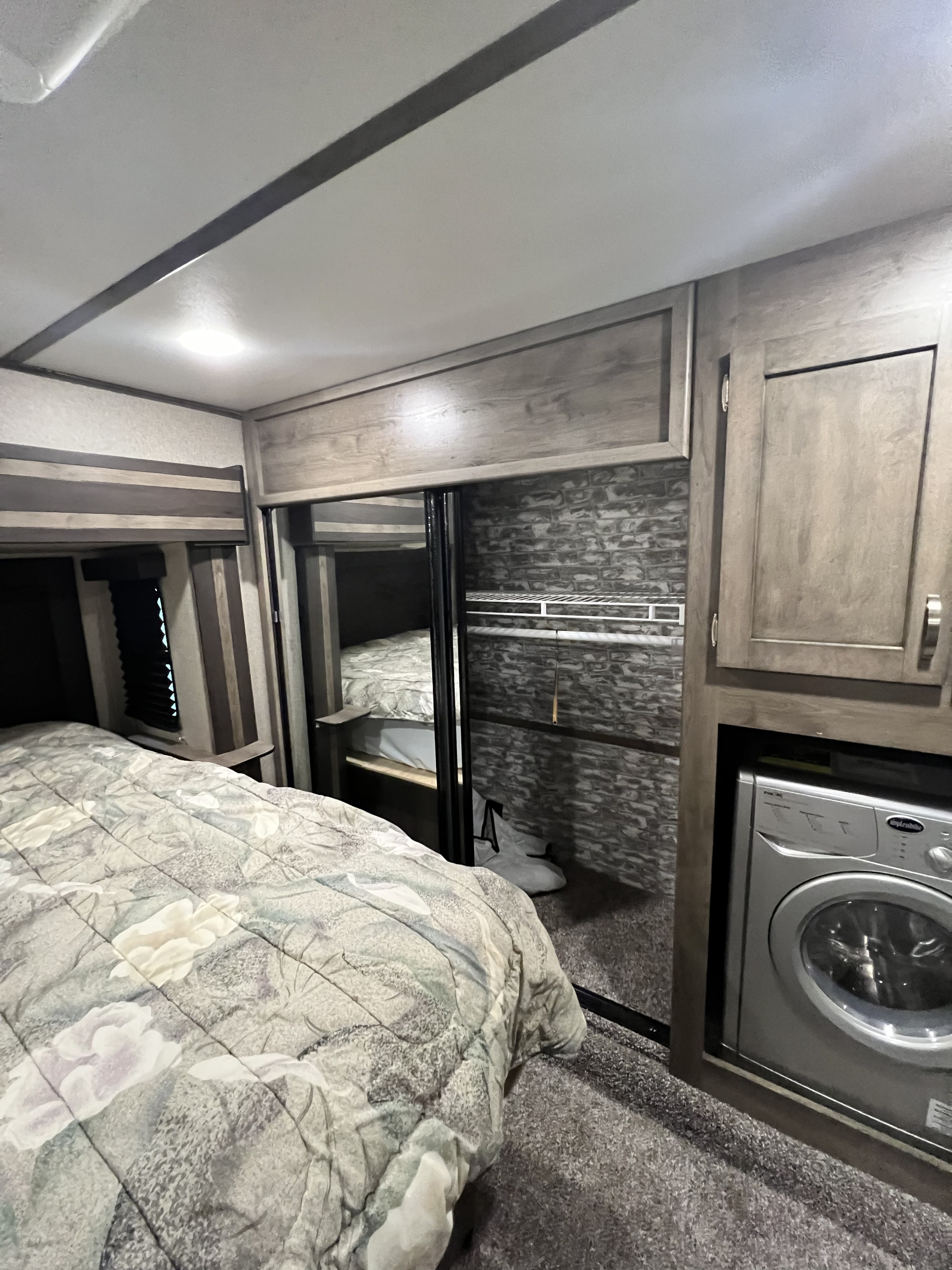 RV rental: Compact bedroom showing a patterned bed, mirrored closet, and built-in washing machine for convenient living.. Keystone Sprinter 2019