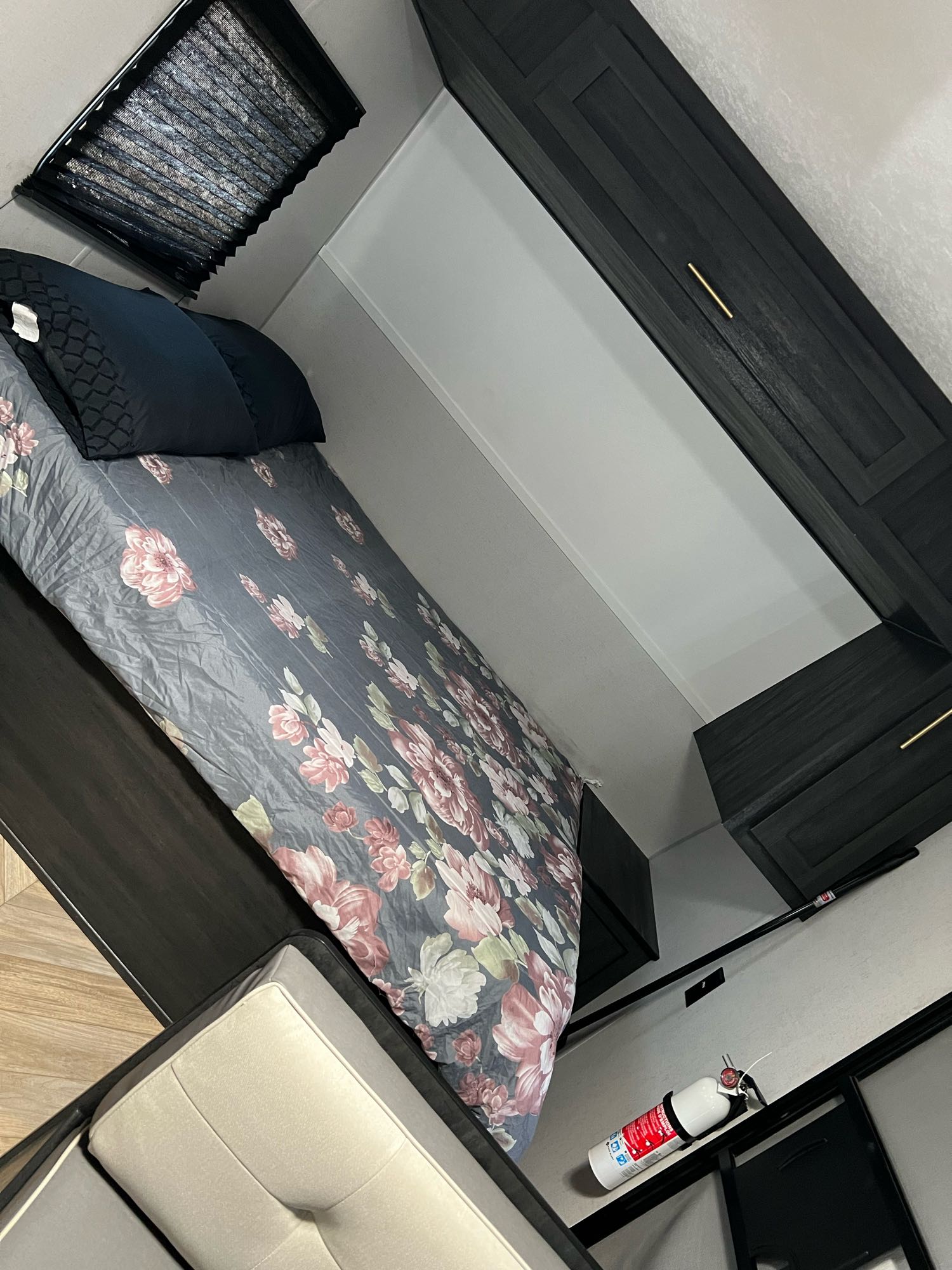 Cozy RV rental bedroom featuring floral bed, dark storage, and safety equipment.. Forest River Ozark 2022