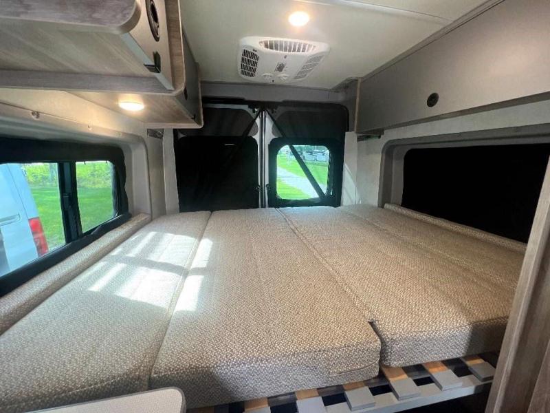 Inside this rv rental: A cozy, modular bed setup with slatted base, overhead storage, and windows offering natural light.. WINNIBAGO SOLIS 2023