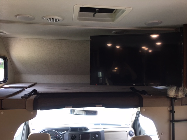 RV rental: Inside, an over-cab bed with safety straps, a mounted TV, and front cabin views are seen. Ideal for road trips.. Forest River Sunseeker LE 2019