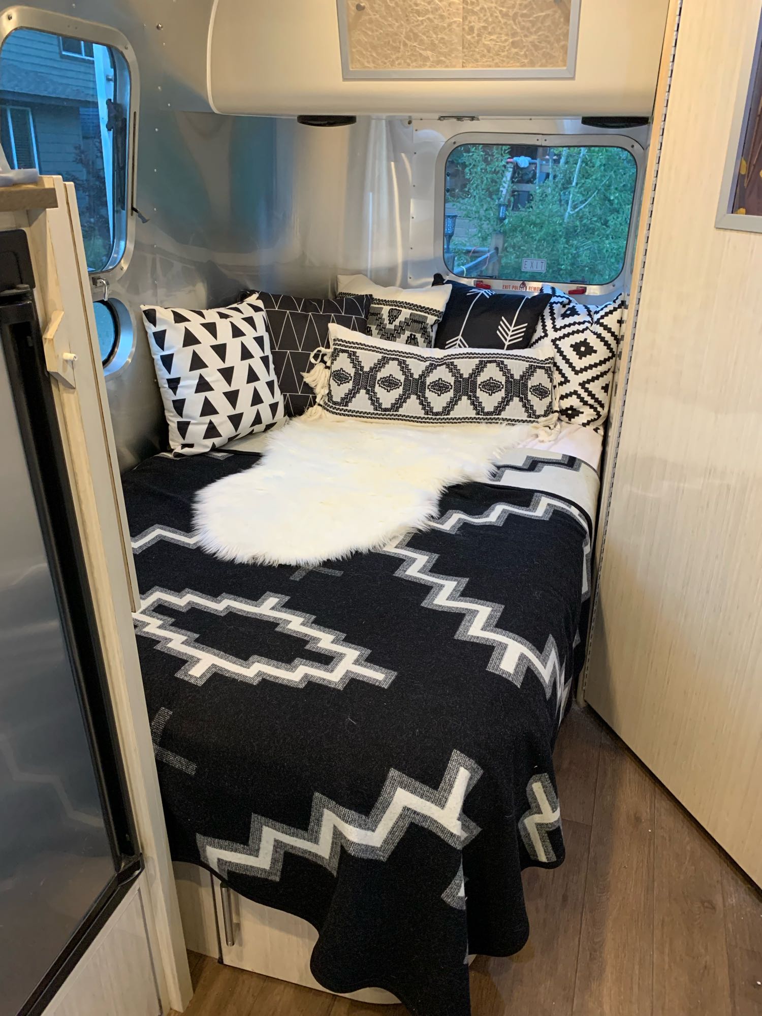 Stylish black and white bed setup in this cozy RV rental interior, complete with decorative pillows and a faux fur throw.. Airstream International 2015