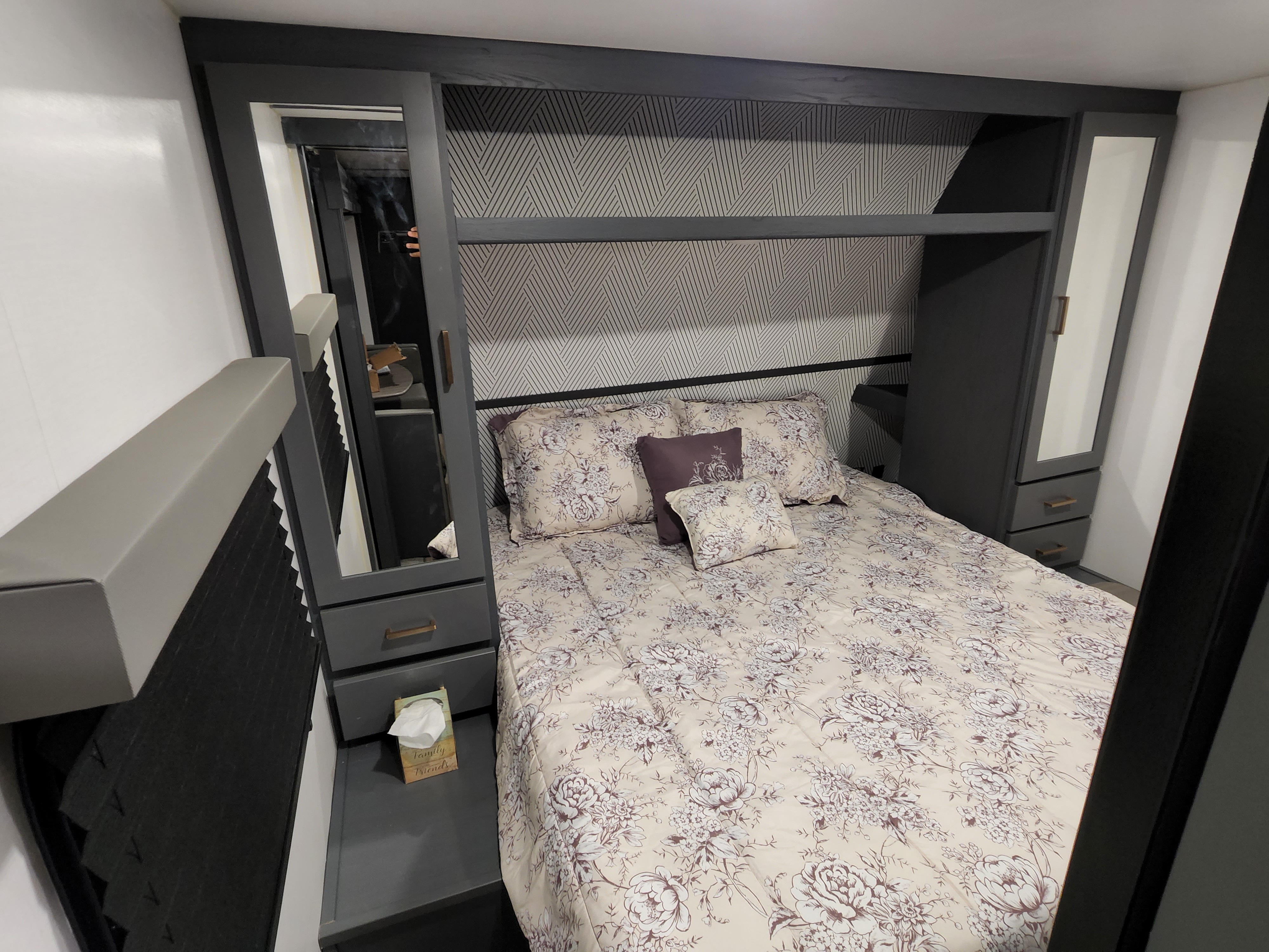 Stylish, compact RV rental bedroom with floral bedding, built-in cabinets, and patterned walls for a cozy stay.. Keystone RV Bullet Crossfire 2022