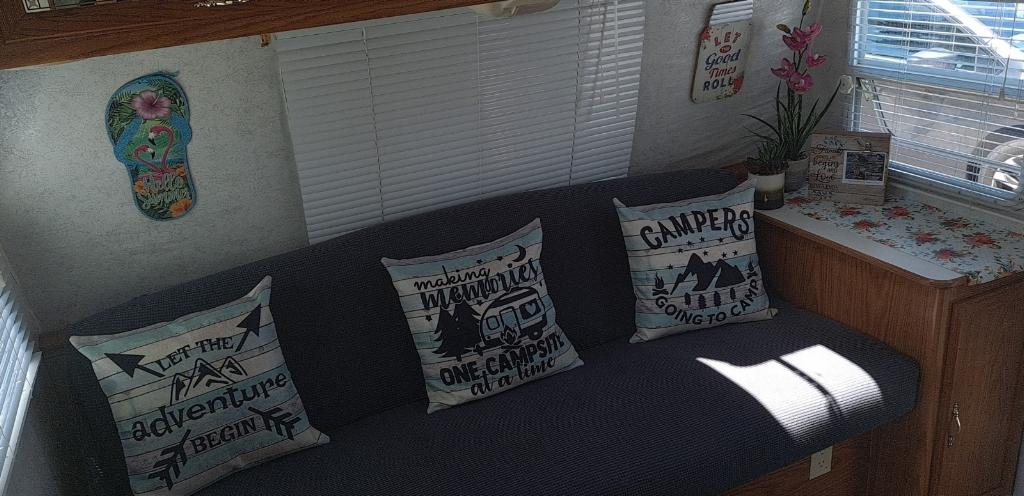Cozy RV rental living space with camping-themed pillows, wall decor, and blinds, ready for adventure.. Shasta Flite 2000