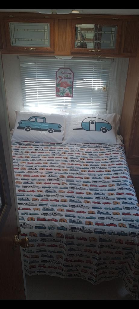 Cozy RV rental bedroom featuring vintage car bedding, a truck pillow, and a teardrop trailer pillow for a fun road trip vibe.. Shasta Flite 2000