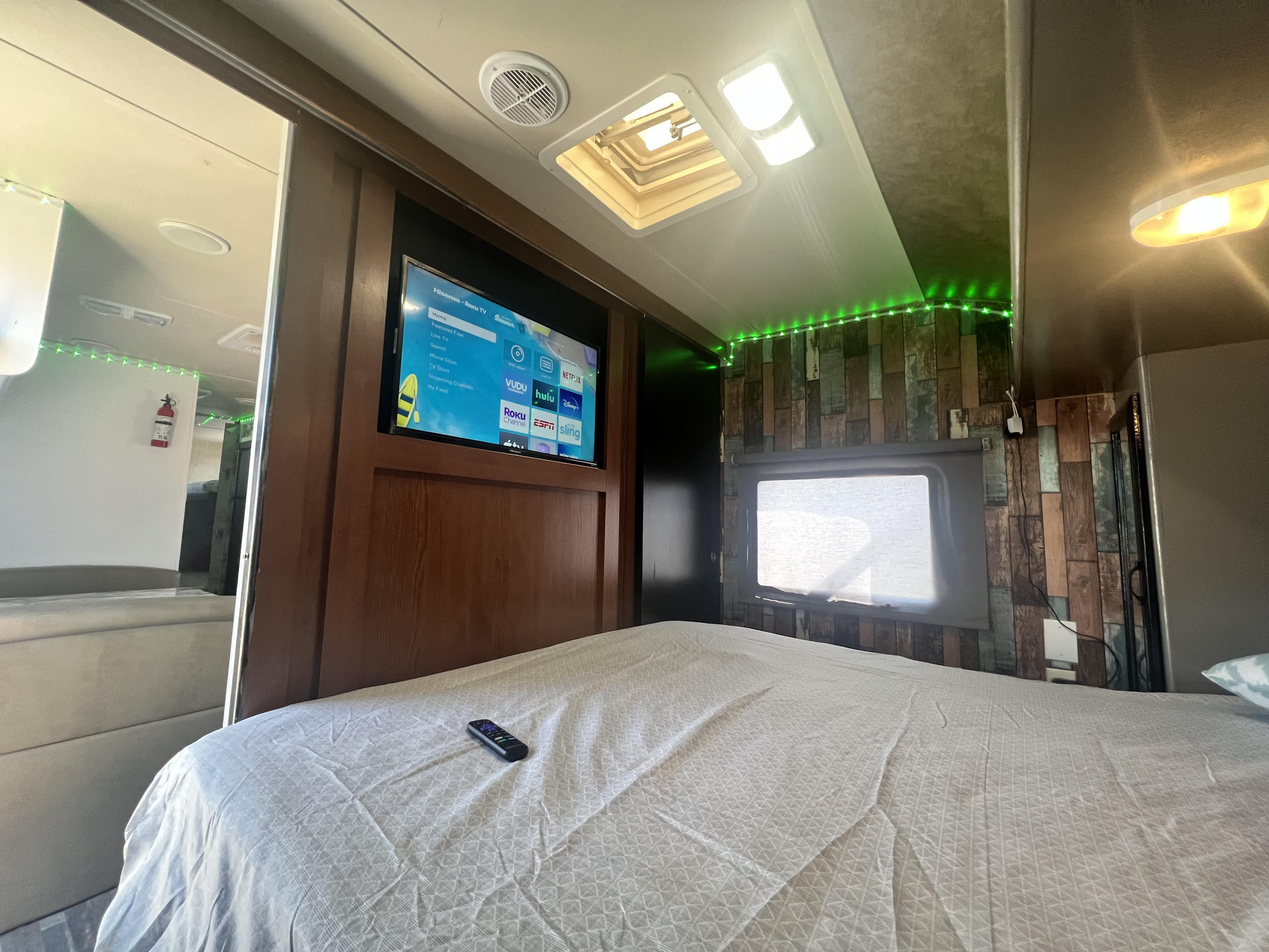 Experience comfort in this RV rental's bedroom, featuring a TV, plush bed, and decorative lighting for your travels.. Forest River Salem Cruise Lite 2014