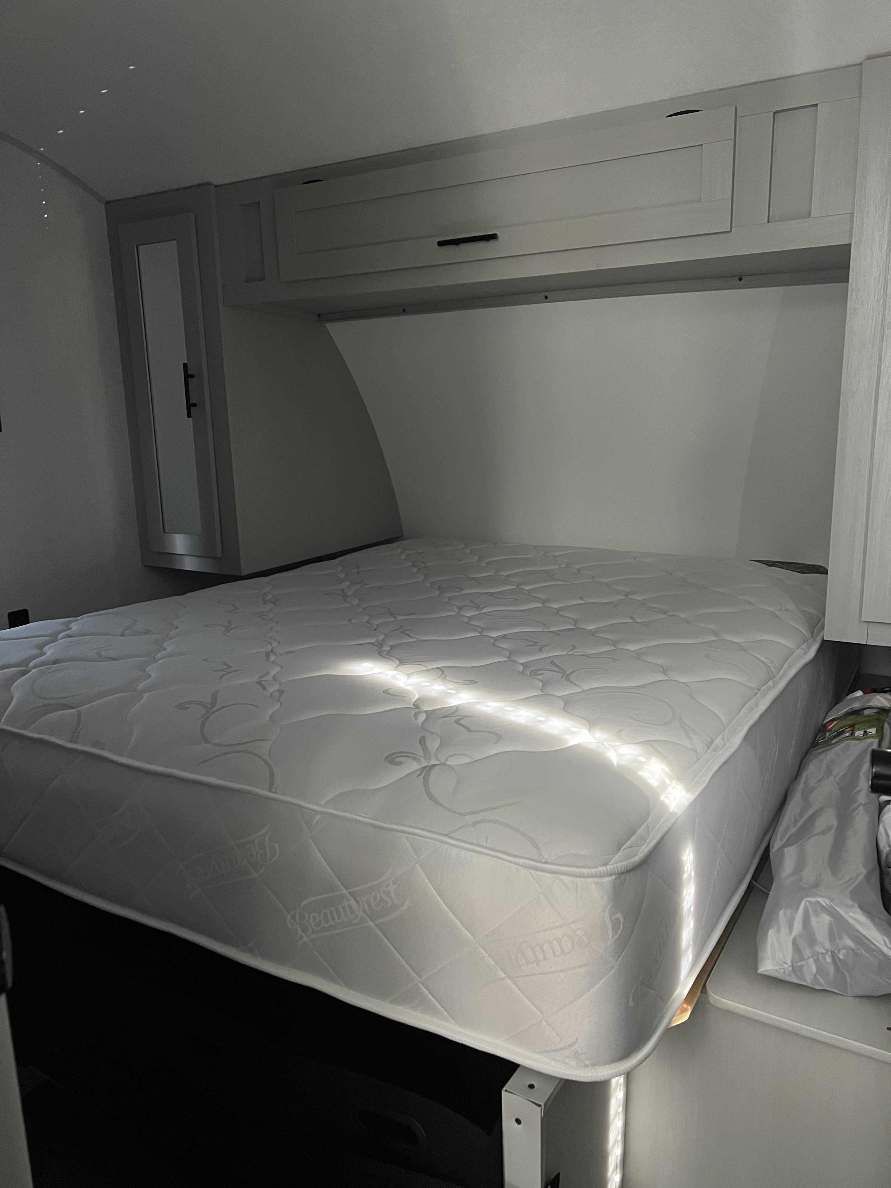 Clean RV rental bedroom featuring a white Beautyrest mattress, overhead cabinets, and bright natural light.. Forest River Salem FSX 270RTKX 2022