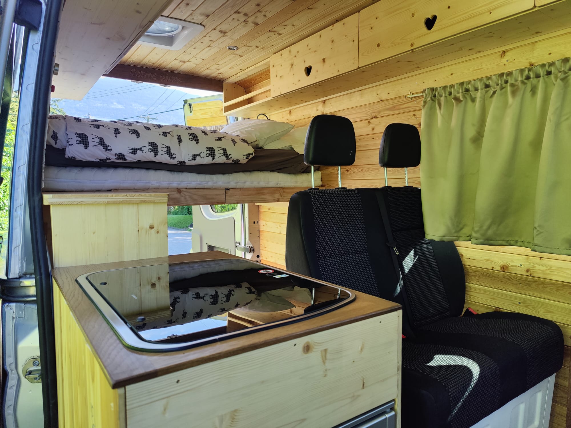 RV rental camper van interior. Features a cozy bed, compact kitchen, and seating, all in warm wood tones.. Mercedes-Benz Sprinter 2006