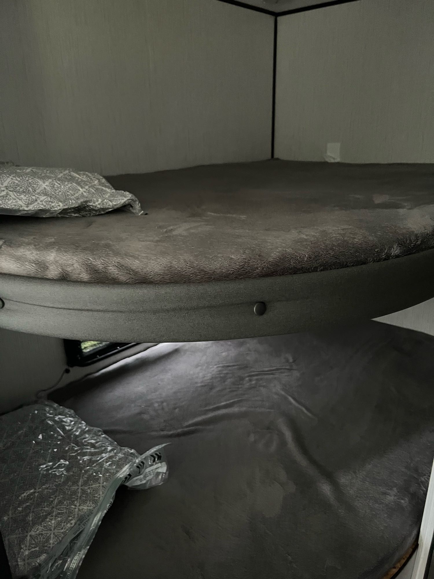 RV rental bunk beds: Cozy gray sleeping area with a patterned pillow and new bedding.. Heartland Prowler 2021