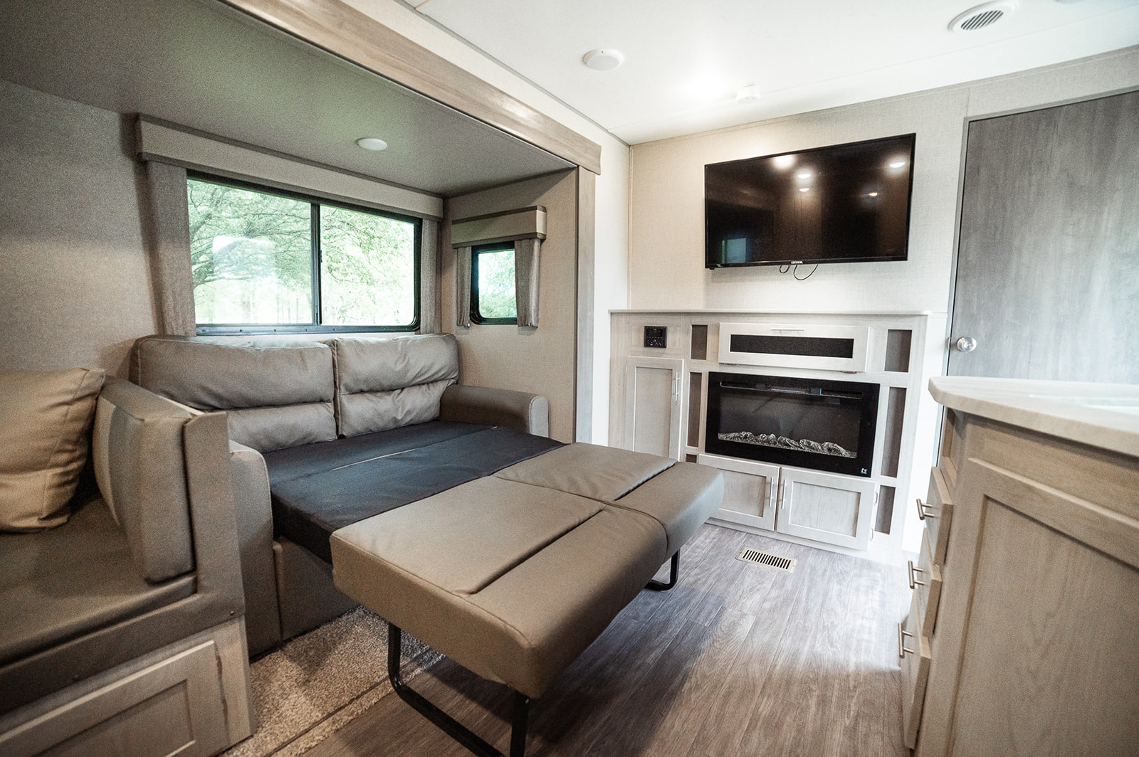 An inviting RV rental living area featuring a sofa bed, electric fireplace, TV, and large windows for scenic views.. Forest River Coachmen Aurora 2022
