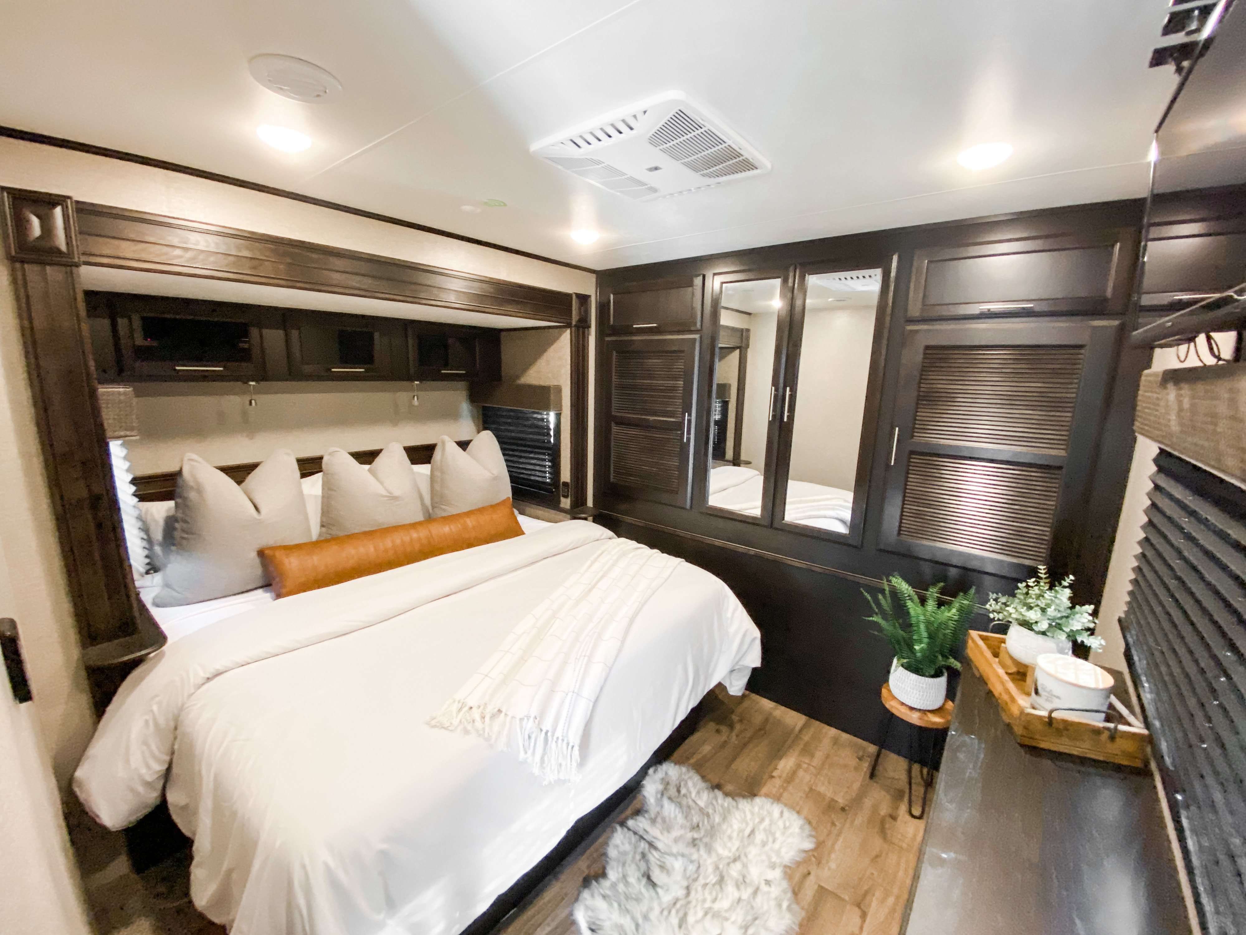 Cozy and modern RV rental bedroom with a comfy bed, dark wood storage, and bright lighting for a relaxing getaway.. Jayco EAGLE 2020