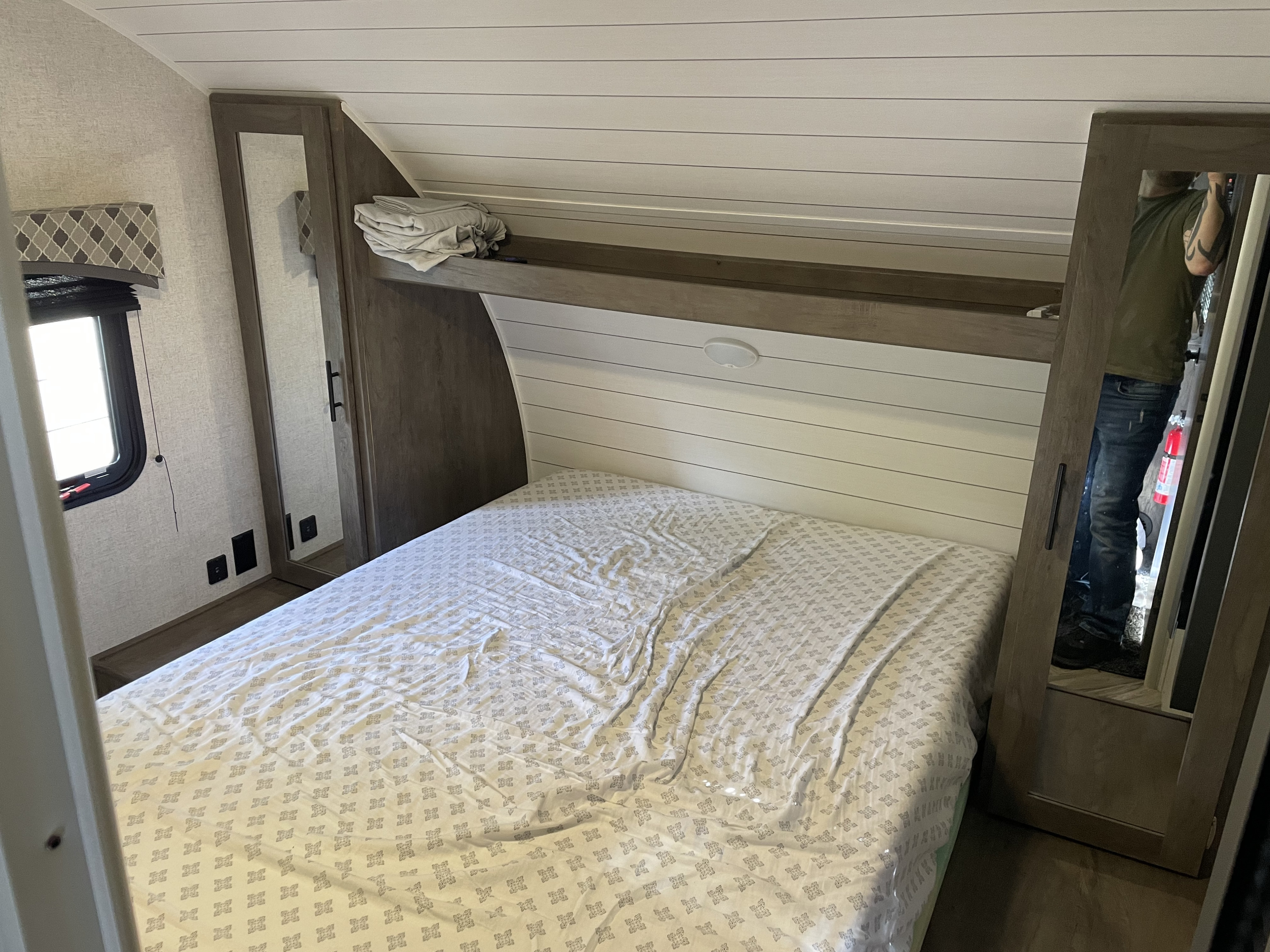 RV rental bedroom featuring a cozy bed, shiplap headboard, and mirrored wardrobes for compact storage.. Forest River EVO 2400BHX 2021