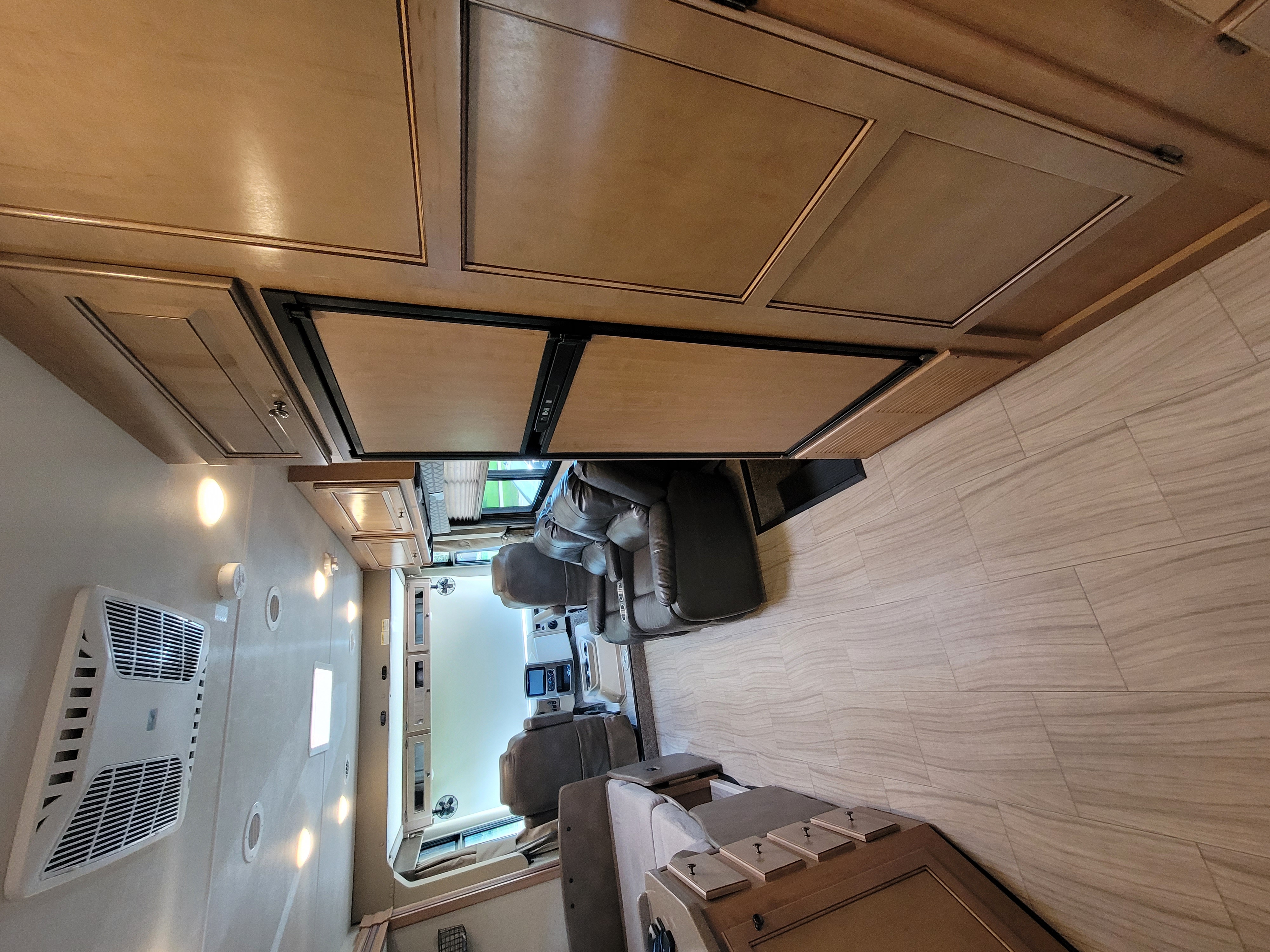 RV rental interior: Overhead wood cabinetry, built-in fridge, light plank flooring & comfortable seating blend.. Thor Windsport 2019