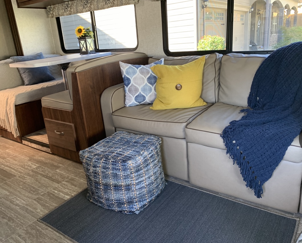 Cozy RV rental interior featuring a comfortable dinette, sofa with pillows and a blue throw, plus a patterned pouf.. Forester LE 2020
