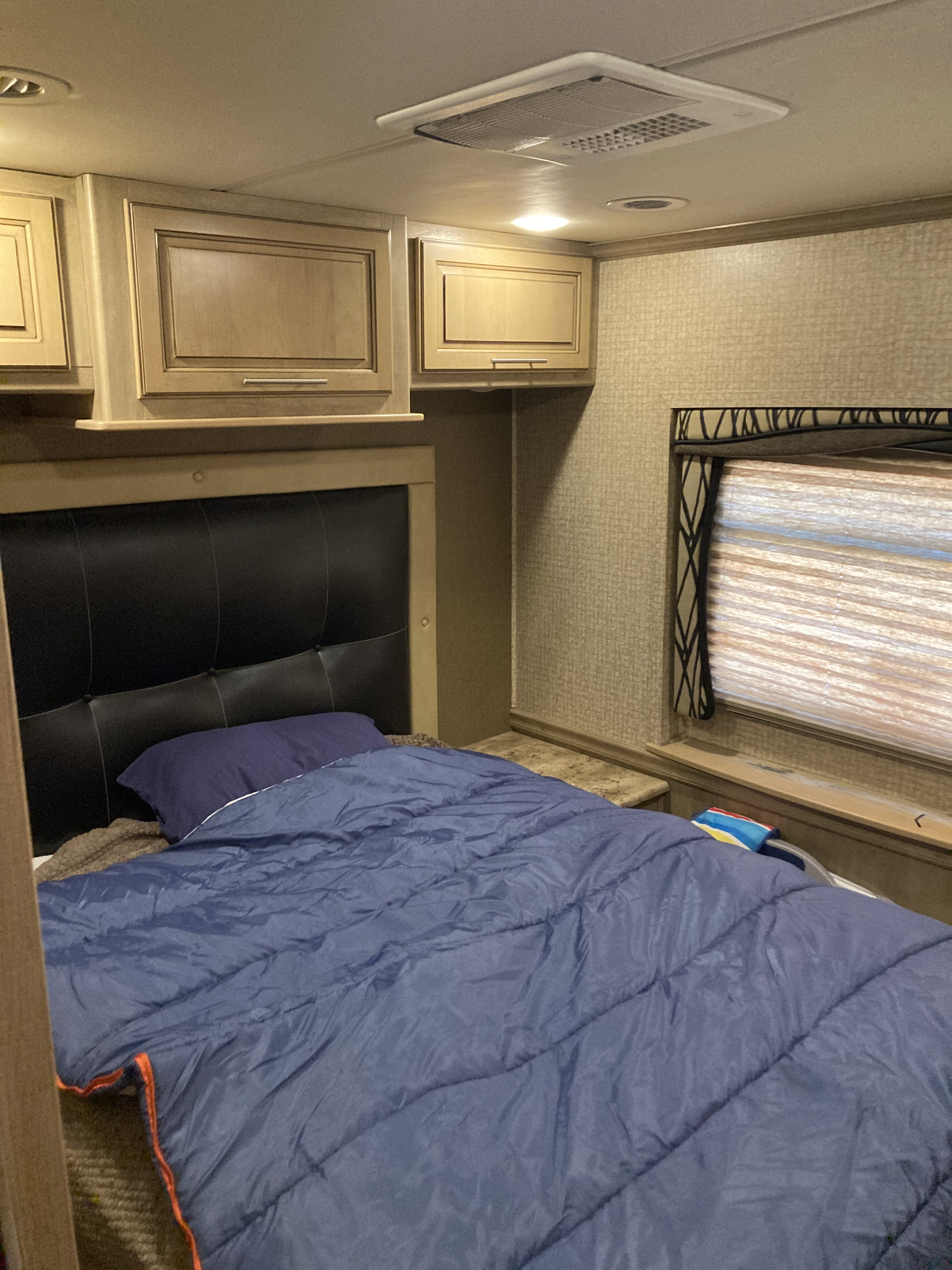 RV rental bedroom with comfortable bed, overhead cabinets, and a window for natural light.. 1F66F5DY4E0A13513 37SA 2015