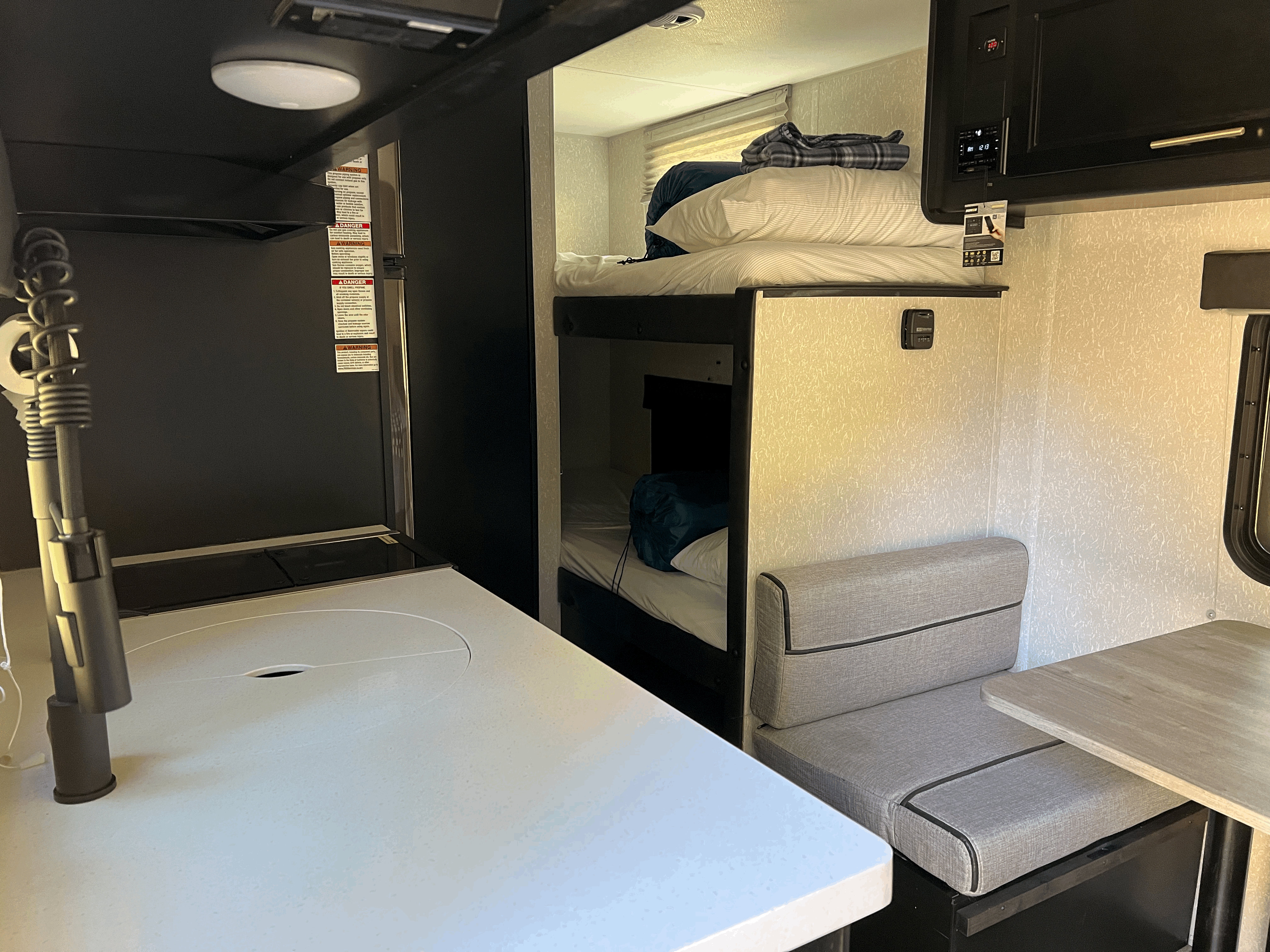 Inside an RV rental: Compact living space with kitchen, bunk beds, and dinette for travelers.. Forest River Cherokee Wolf Pup Black Label 2022