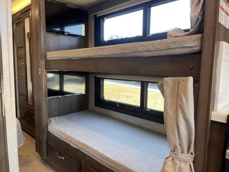 Comfortable RV rental interior: wooden bunk beds, each with a TV, and built-in storage.. Entegra Coach Vision 2023