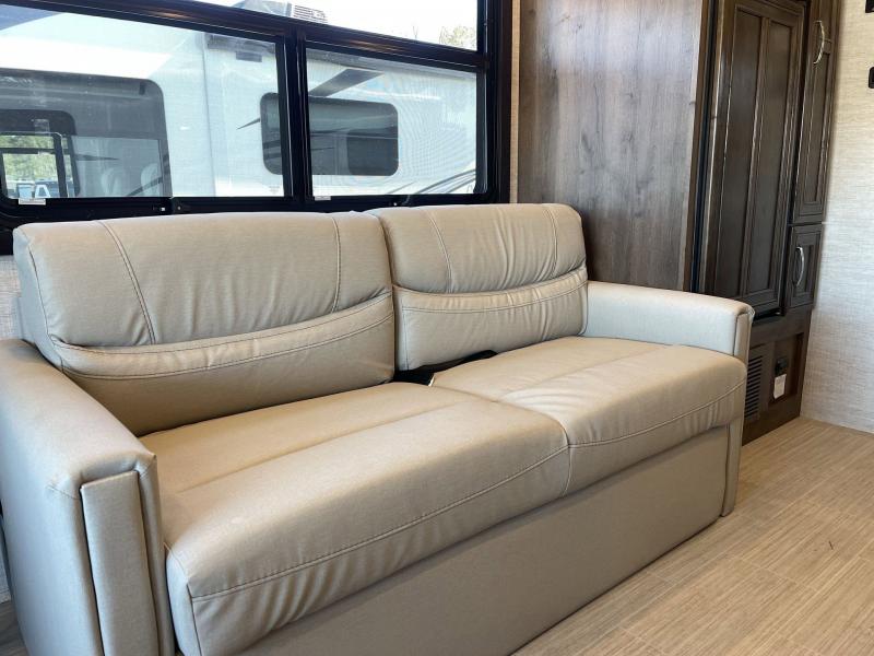 RV rental's inviting living area with a plush light sofa, panoramic windows, and functional storage cabinetry.. Entegra Coach Vision 2023