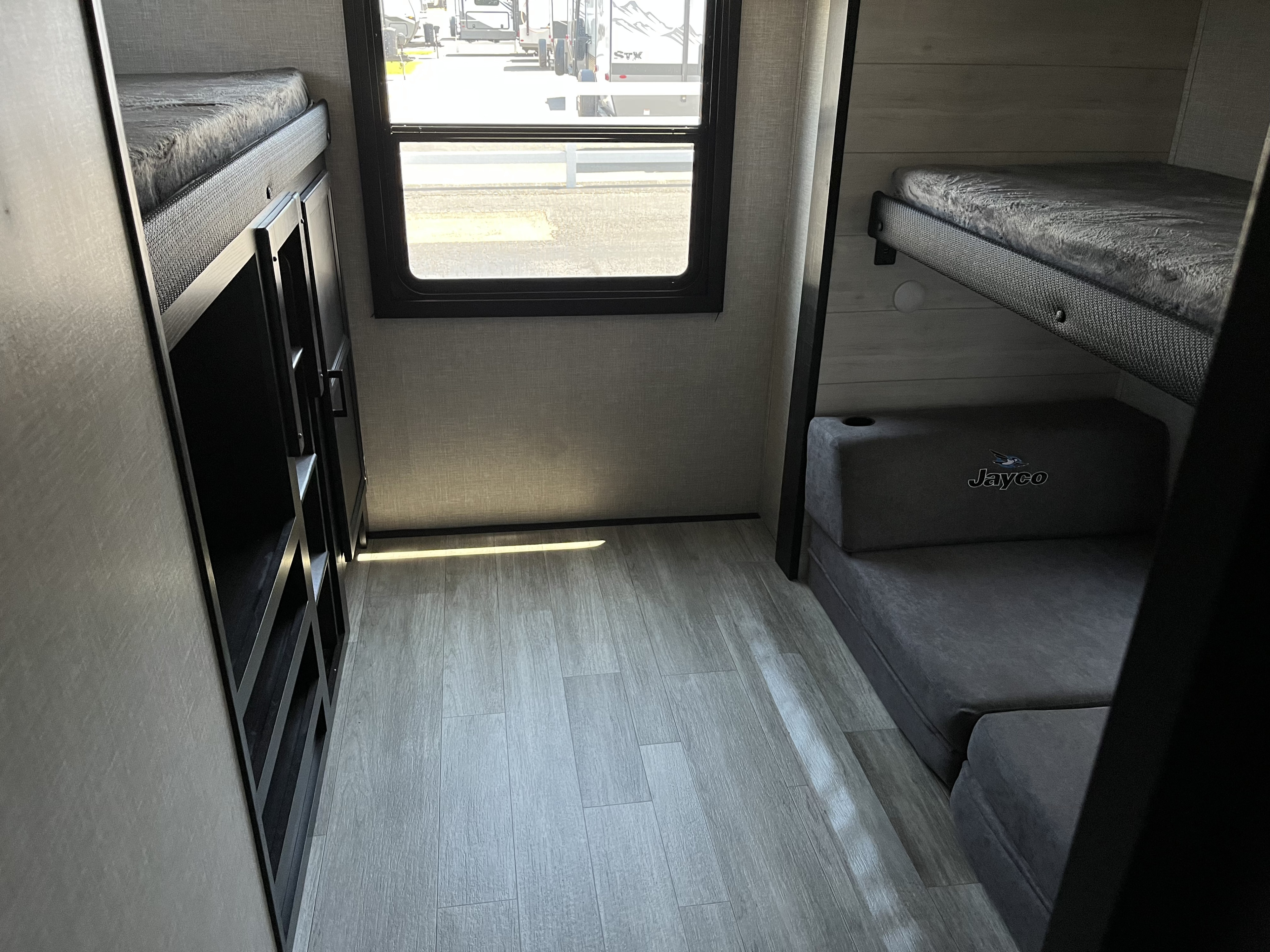 RV rental bunk beds, Jayco sofa, and storage in a compact travel trailer bunkhouse. Window offers views.. Jayco Jay Flight SLX 2022