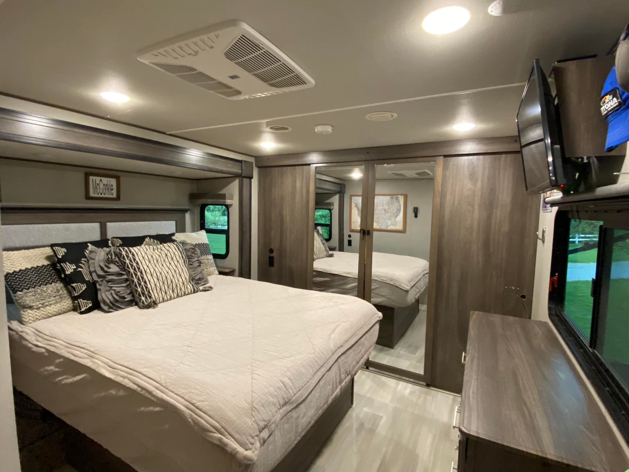 Cozy, well-lit RV rental bedroom featuring a large bed, mirrored closet, TV, and light flooring. Spacious for travel comfort.. Grand Design Solitude 2021