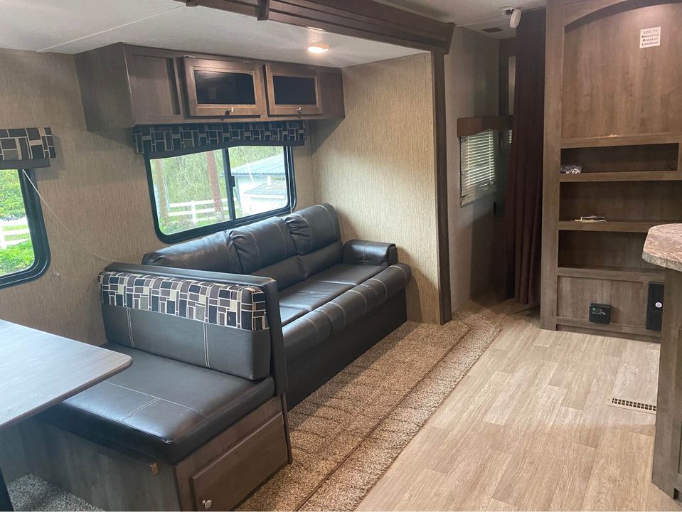 Inside this RV rental: a comfortable living area with dinette seating, large windows, and a plush couch. Ready for your trip.. Dutchmen Coleman Lantern 2018