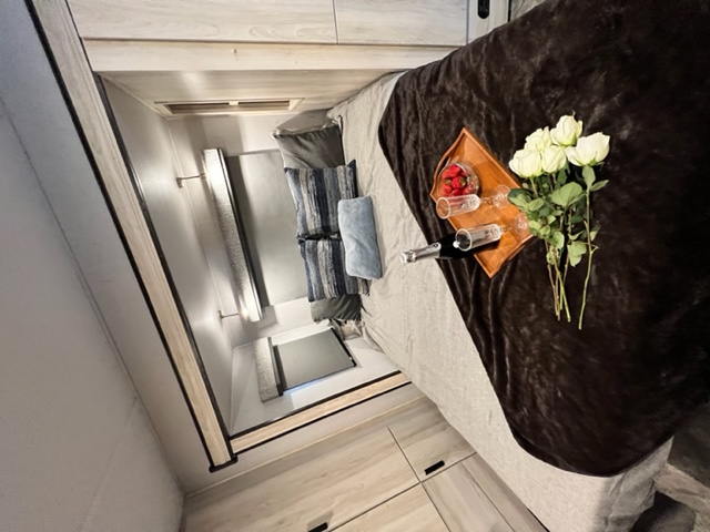 Cozy RV rental bedroom with a romantic setup: champagne, strawberries, and white roses on the bed.. Forester MBS 2022