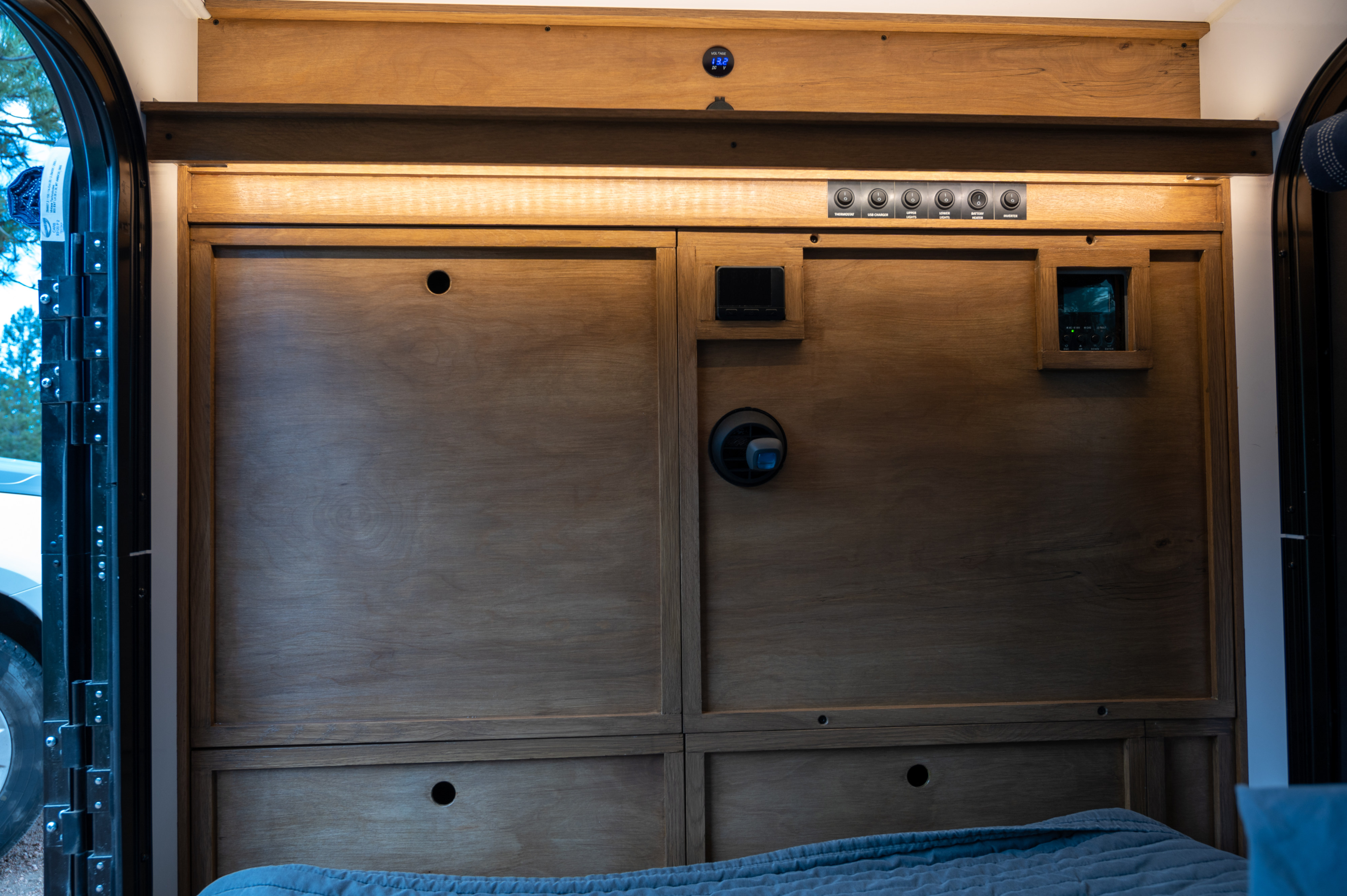 RV rental interior: wooden panels, power controls, thermostat, and bed, providing comfort and functionality.. White River X Camper Trail Explorer 2021