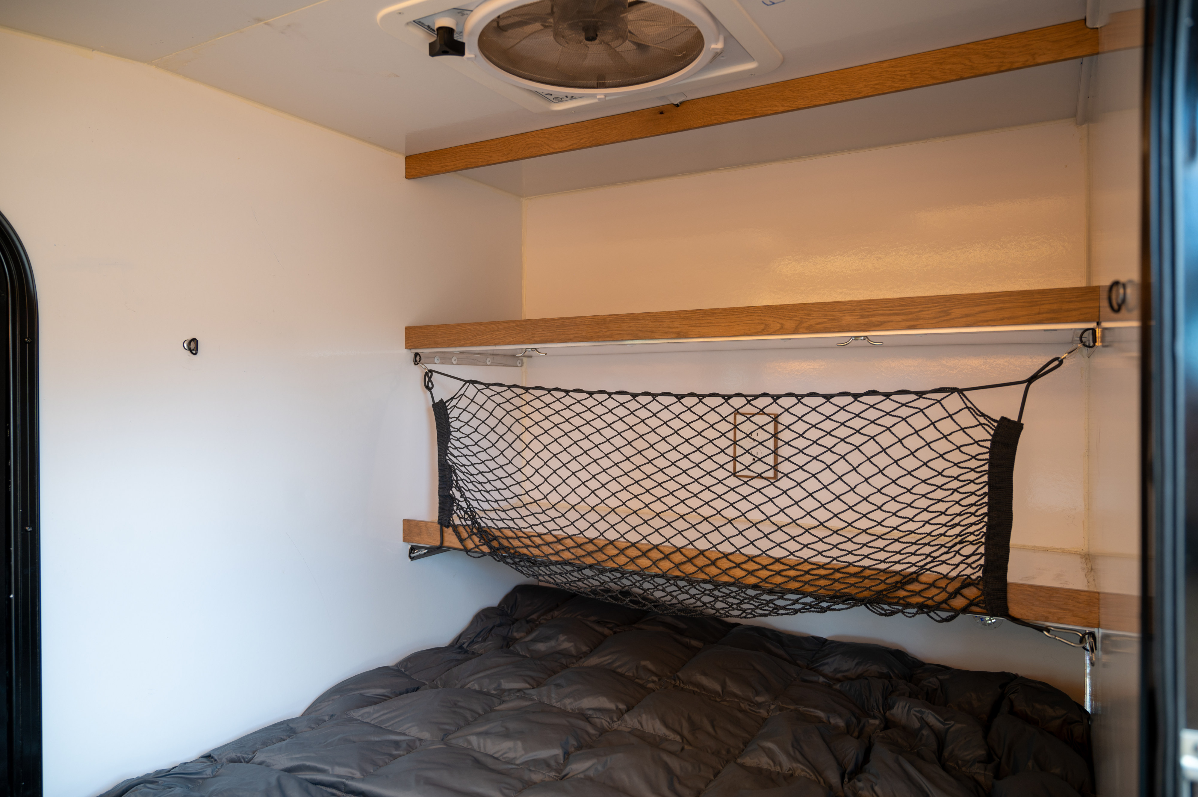 Cozy RV rental interior with a bed, overhead shelf, and practical cargo net storage.. White River X Camper Trail Explorer 2021