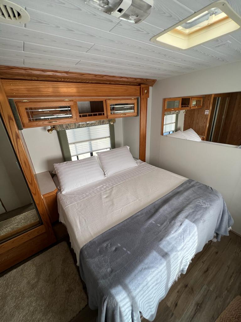 Comfortable RV rental bedroom with spacious bed, overhead storage, and natural light. Perfect for your next adventure.. Gulf Stream Sun Voyager 2001