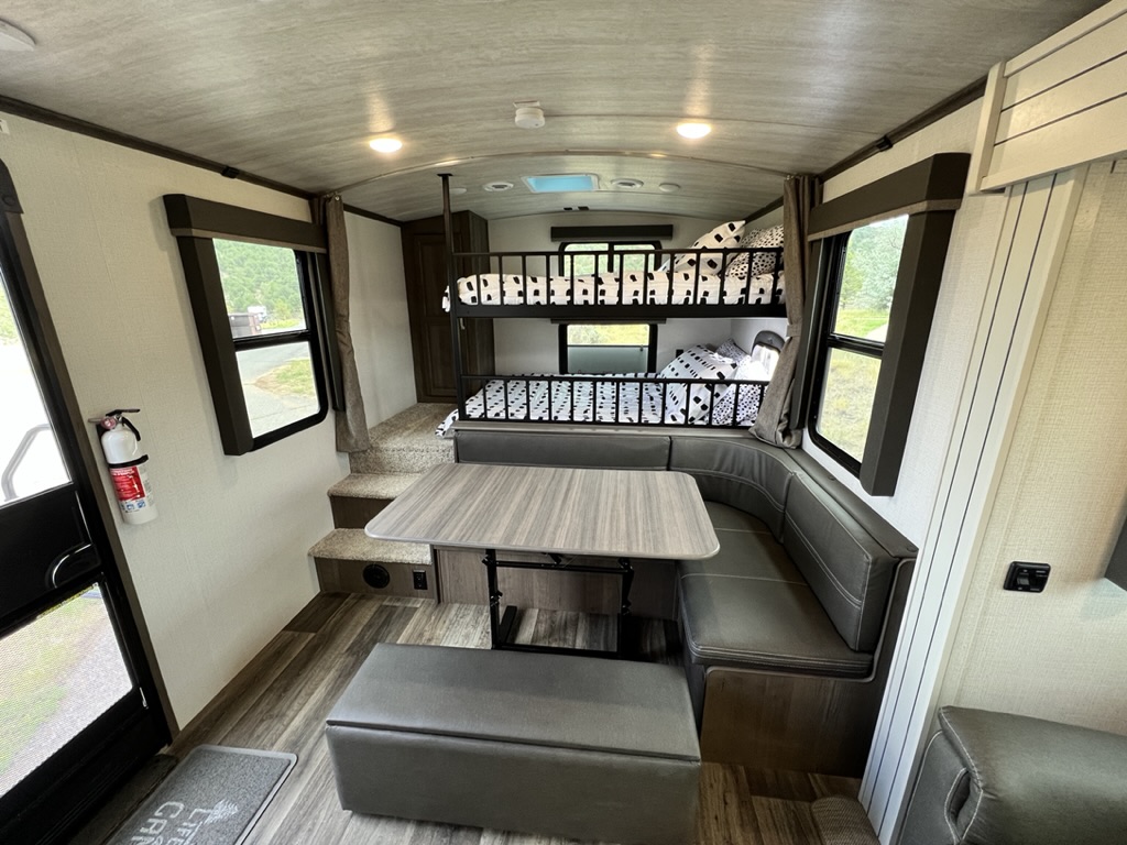RV rental interior with bunk beds, a U-shaped dinette, and comfortable seating. Ideal for family trips.. Keystone RV Cougar 2022