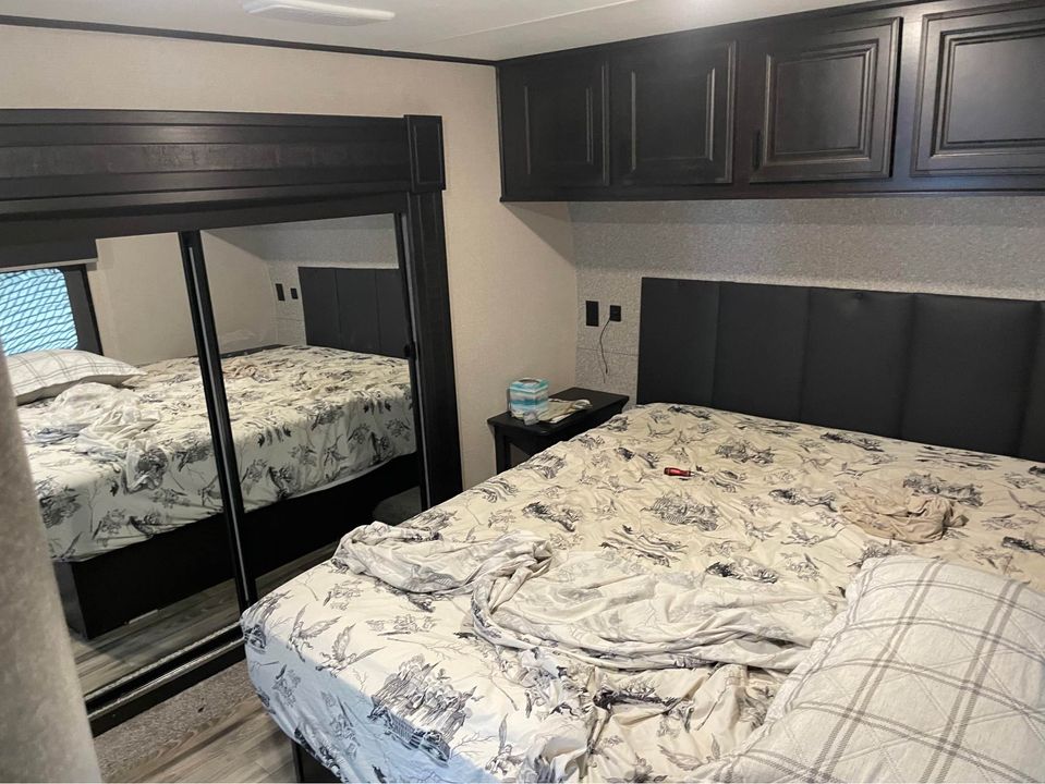 Spacious RV rental master bedroom featuring a large bed, mirrored closet, and ample storage cabinets.. Highland Ridge RV Open Range 2022