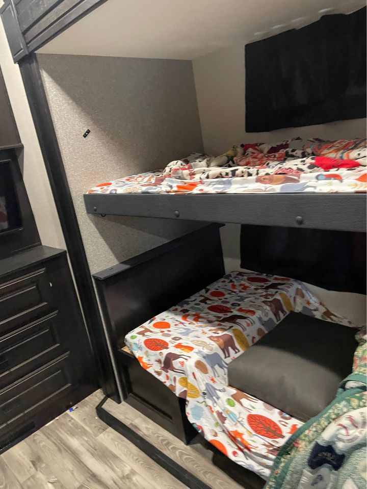 This RV rental features cozy bunk beds with animal-patterned bedding, a dresser, and a TV, perfect for family adventures.. Highland Ridge RV Open Range 2022