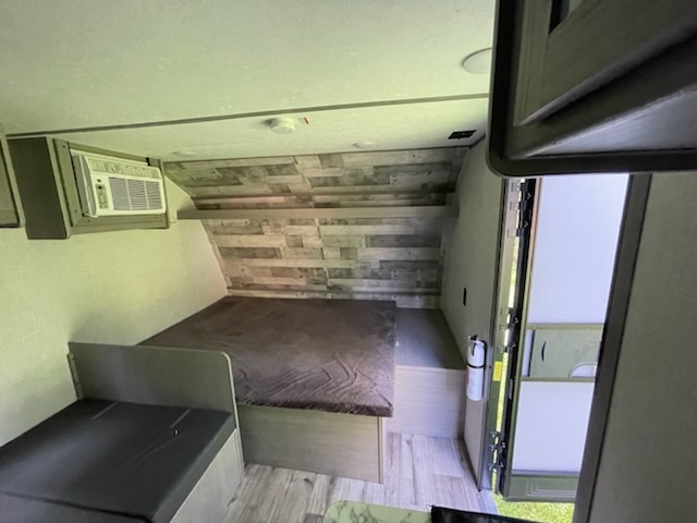 Compact travel trailer RV rental interior: bed, AC unit, seating. Ready for adventure.. Dutchmen Coleman Lantern LT 2022
