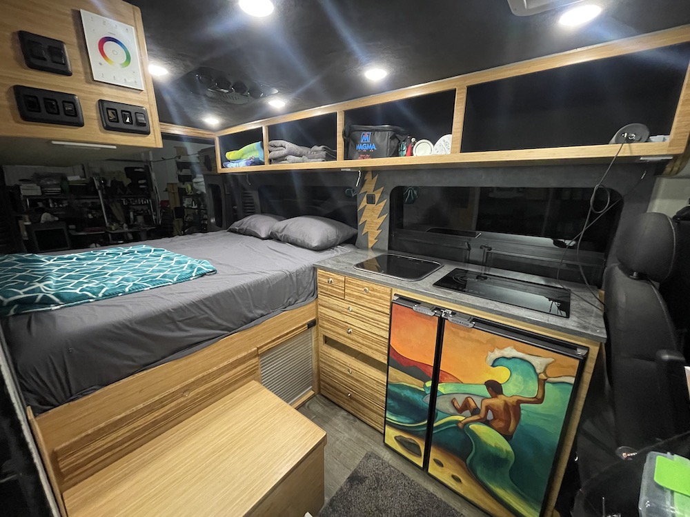 Custom camper van rv rental: enjoy a cozy bed, full kitchenette, and distinctive surfing fridge art in this mobile home.. Ram Promaster 2017