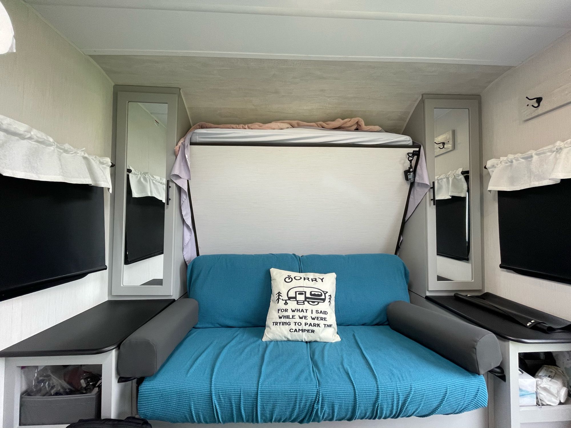 RV rental: Compact interior with a blue sofa/bed, upper bunk, storage, and mirrors.. Forest River Vibe 2022