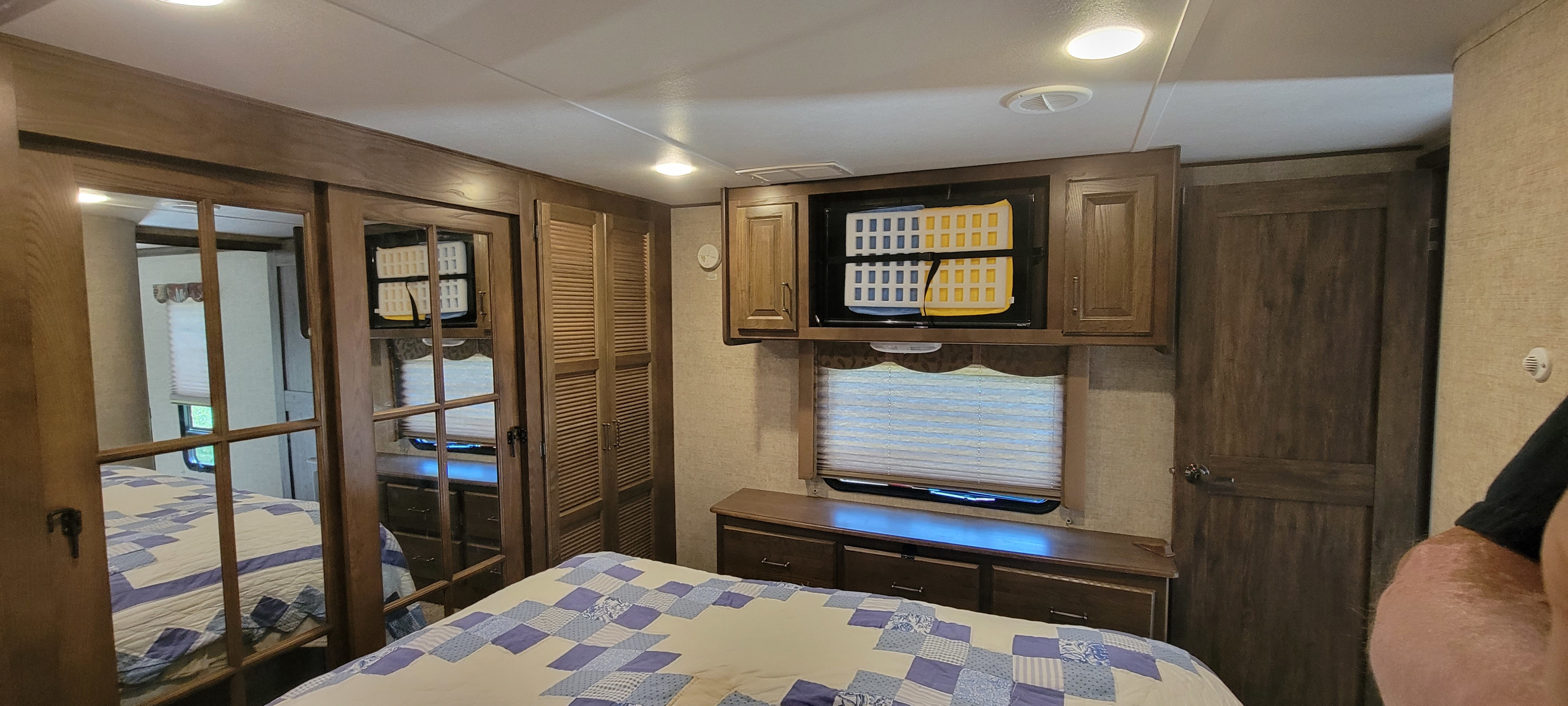 Spacious RV rental bedroom with a comfy bed, TV, storage, and mirrored closets for a relaxing road trip experience.. Keystone RV Alpine 2015