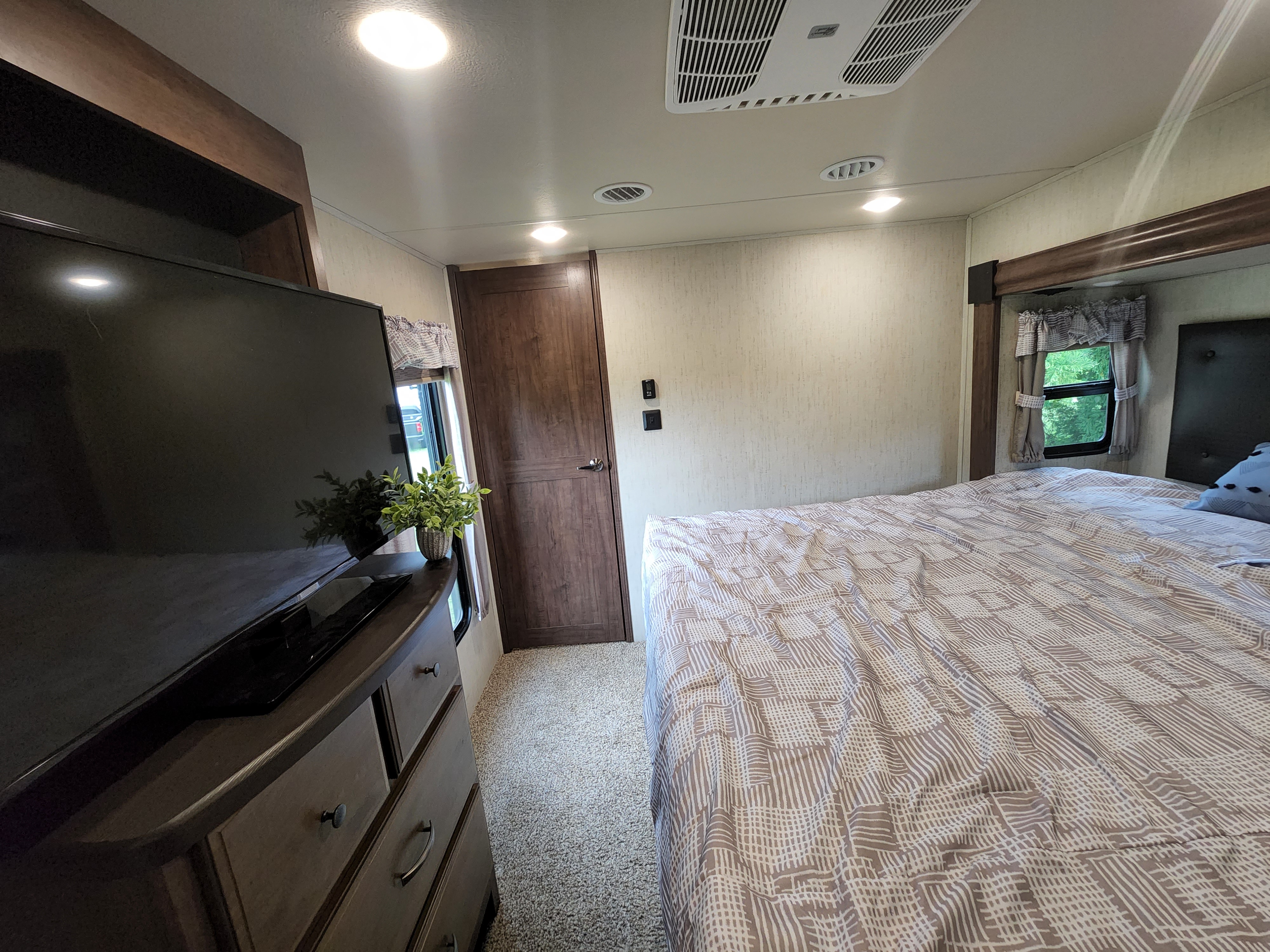 Cozy RV rental bedroom with a large bed, TV, dresser, and AC, perfect for a comfortable road trip stay.. Forest River Sierra 2020