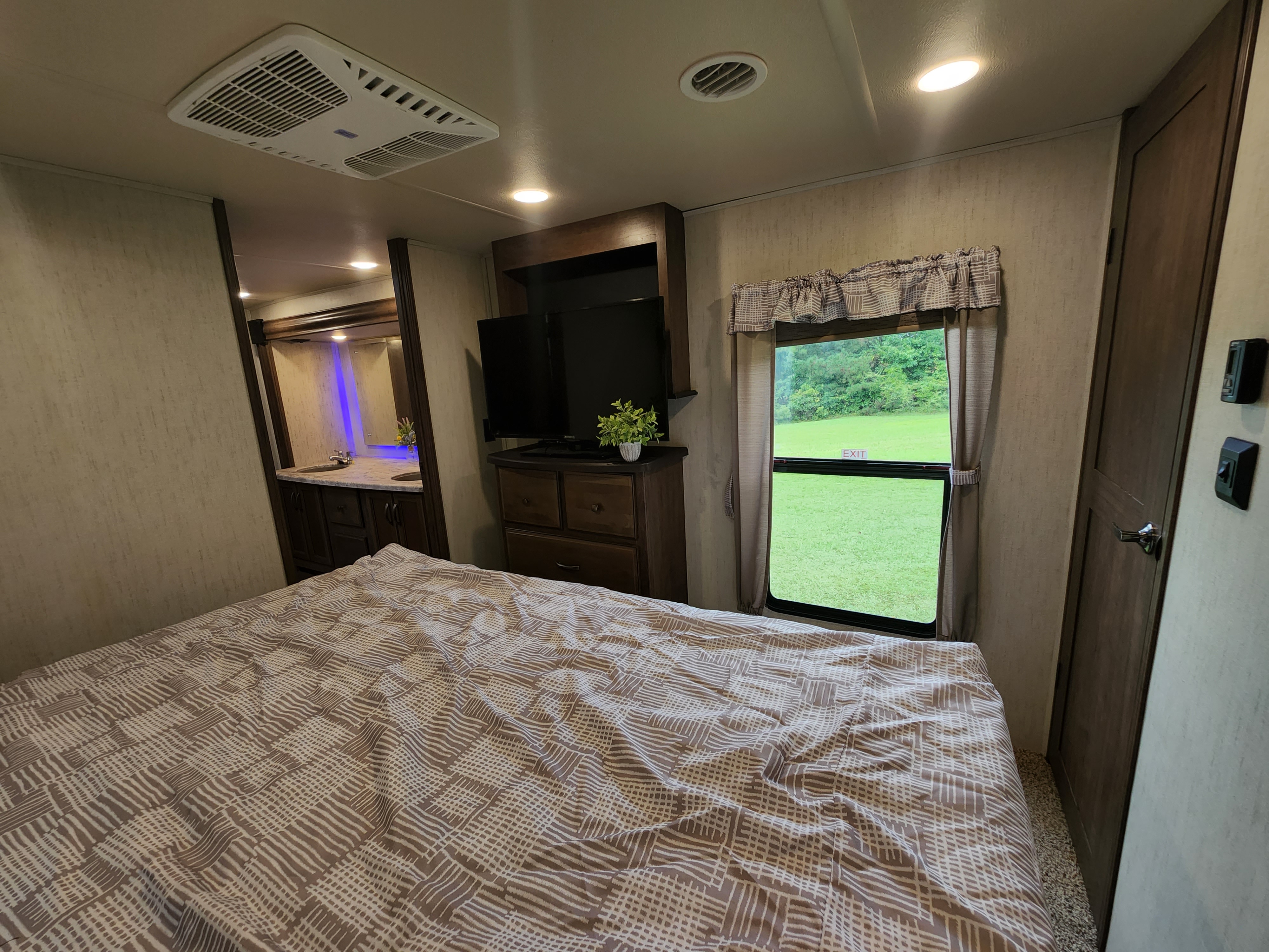Spacious RV rental bedroom with TV, vanity, and large window offering outdoor views.. Forest River Sierra 2020