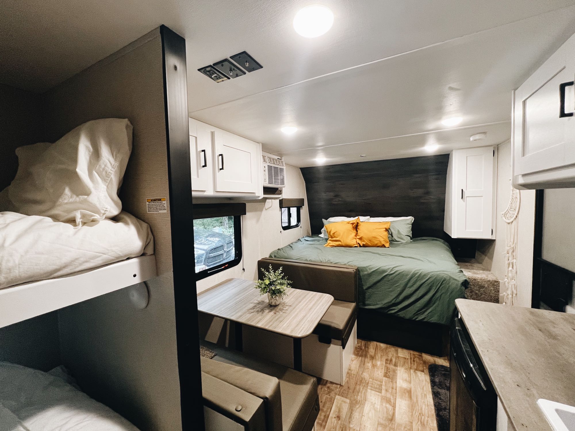 Spacious RV rental interior with a main bed, dining area, and bunk beds, ideal for family travel.. Keystone RV Hideout 2022